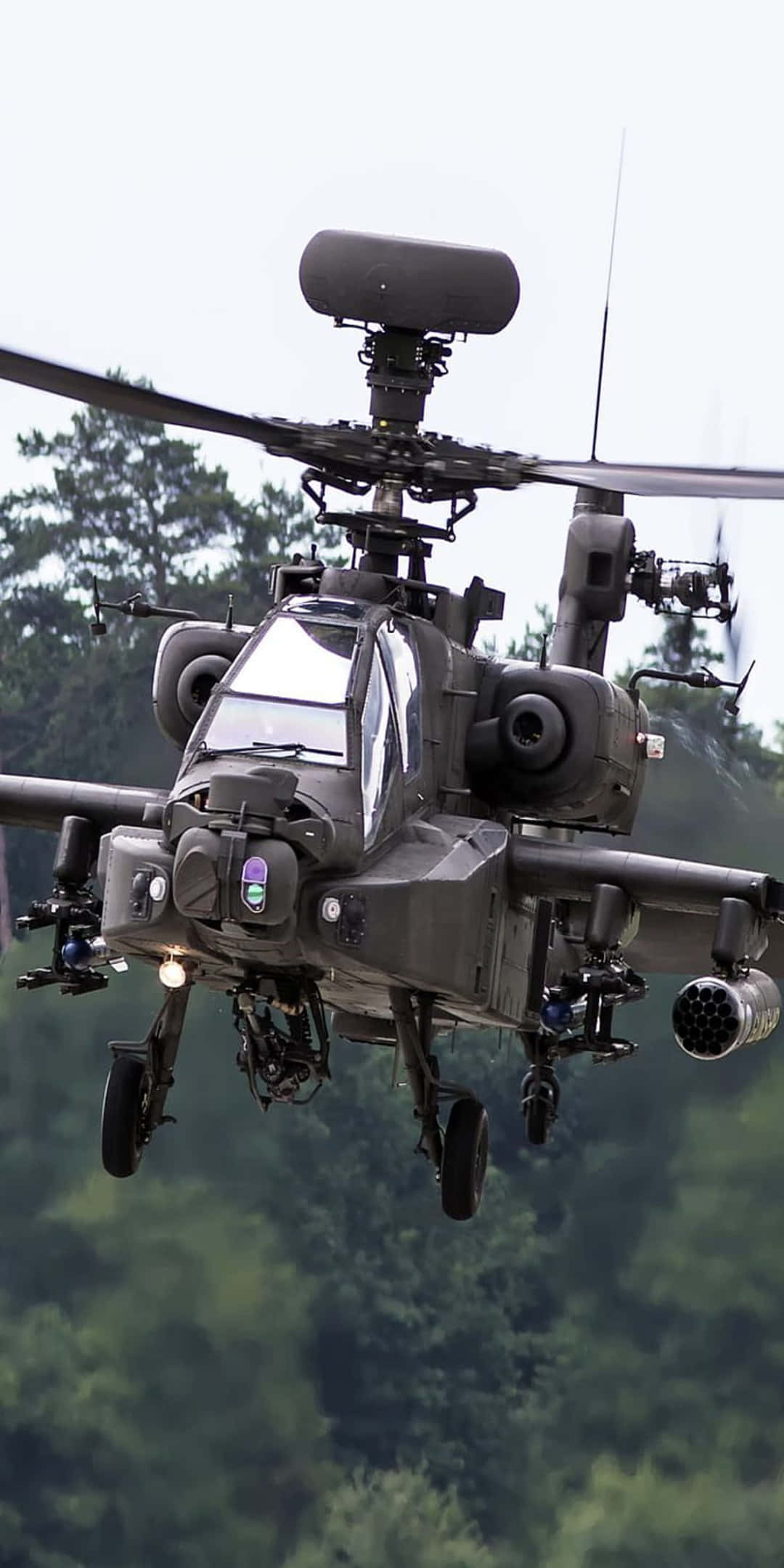 Helicopter 桌布 壁紙 — 一架軍用攻擊直升機在陰天低空盤旋於茂密的綠色森林樹冠之上。