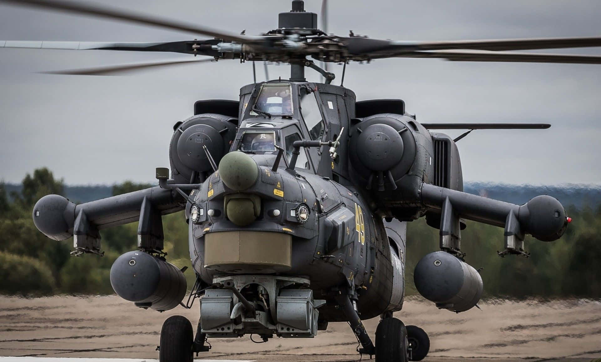 Helicopter 桌布 壁紙 — 一架軍用攻擊直升機旋轉著旋翼，停在一片泥地上，天空多雲。