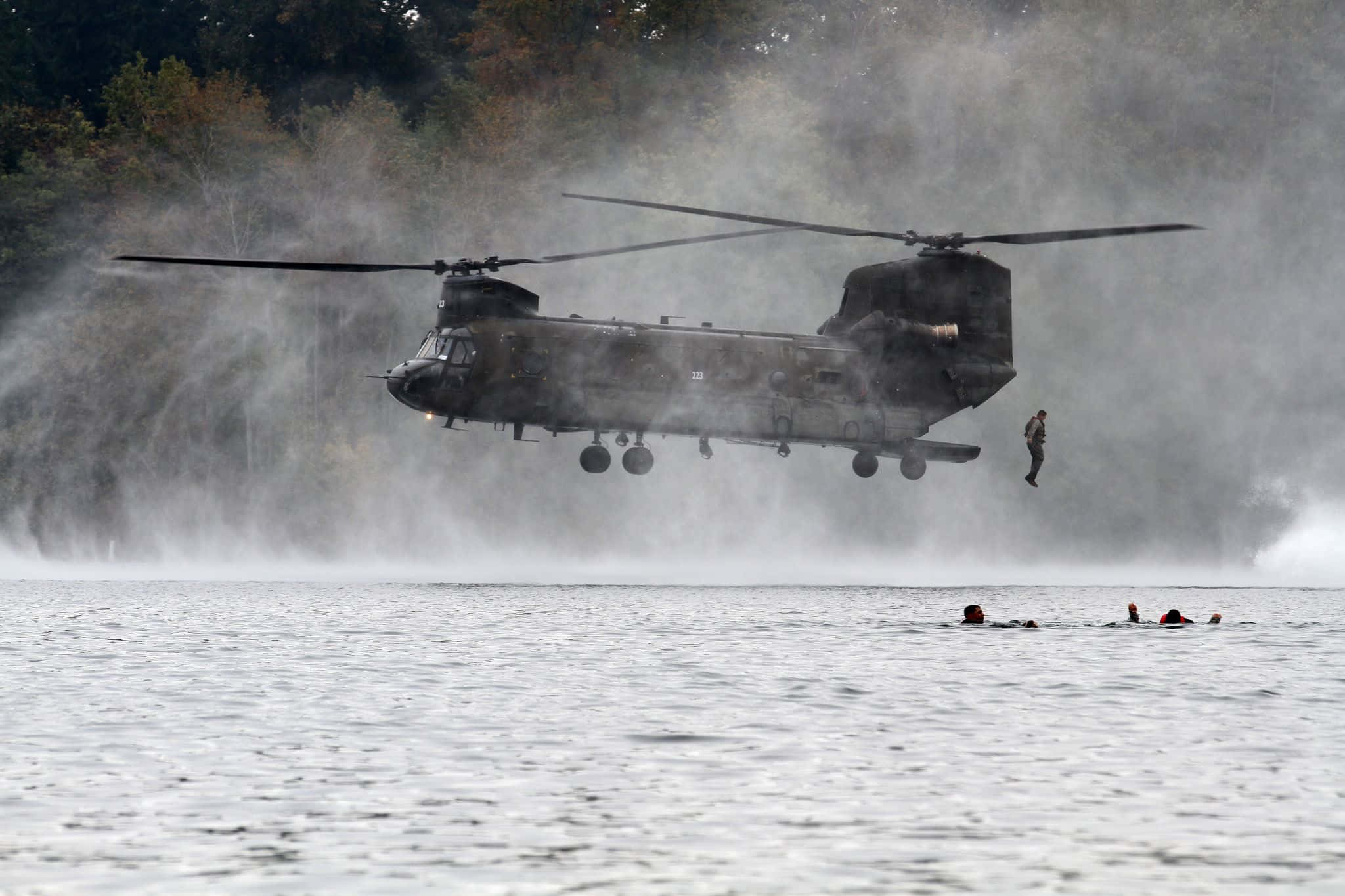 transportation 桌布 壁紙 — 一架軍用直升機低空盤旋在湖面上，一名士兵正在垂降，其他士兵在附近霧中游泳。