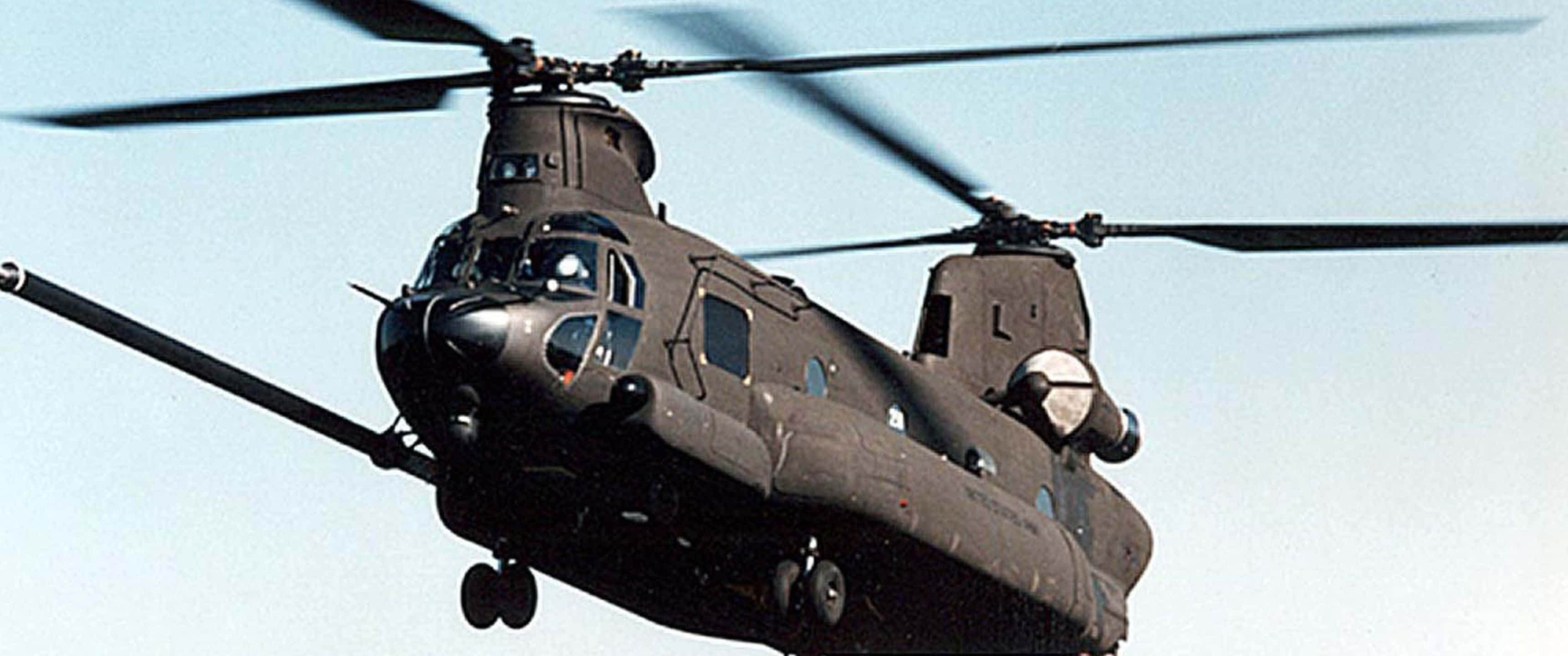 3440x1440p Helicopters 桌布 壁紙 — 一架軍用直升機在晴朗的藍天下飛行，旋翼轉動，起落架放下。