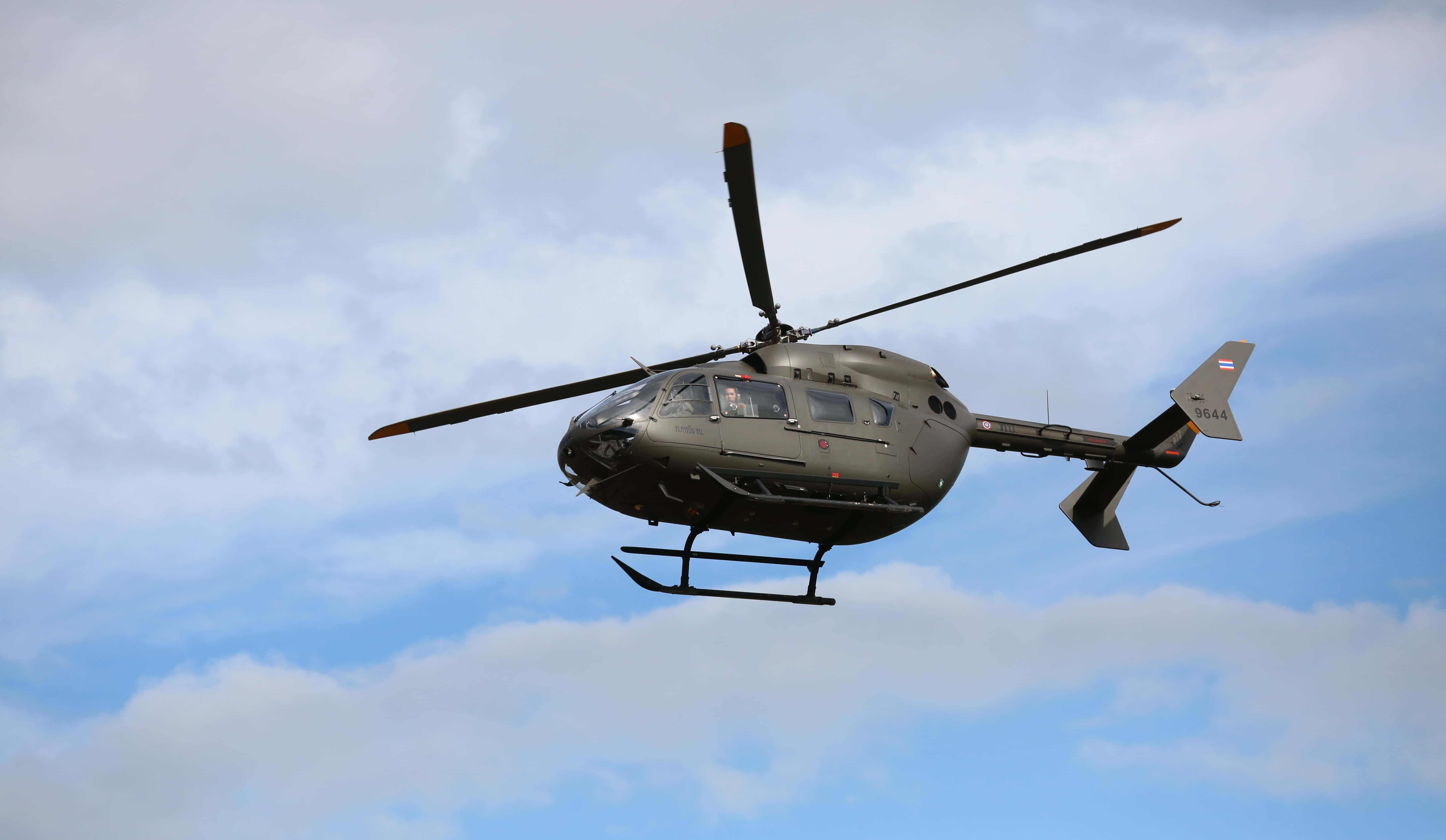 Helicopter 桌布 壁紙 — 一架軍用直升機在部分多雲的藍天中飛行，旋翼轉動。