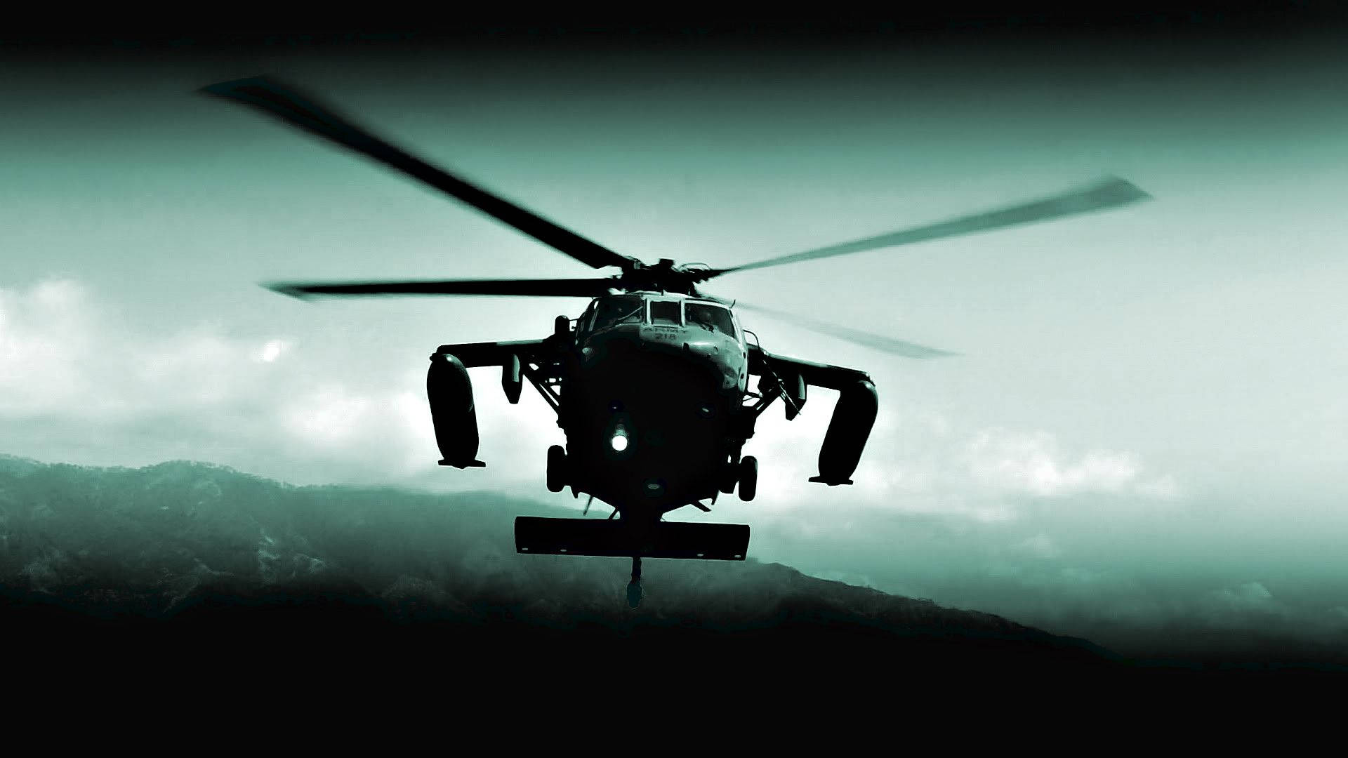Black Hawk Helicopter 桌布 壁紙 — 一架軍用直升機在陰雲密佈的天空襯托下，以剪影姿態盤旋於黑暗山脊之上，呈現出帶有綠色調的陰鬱場景。