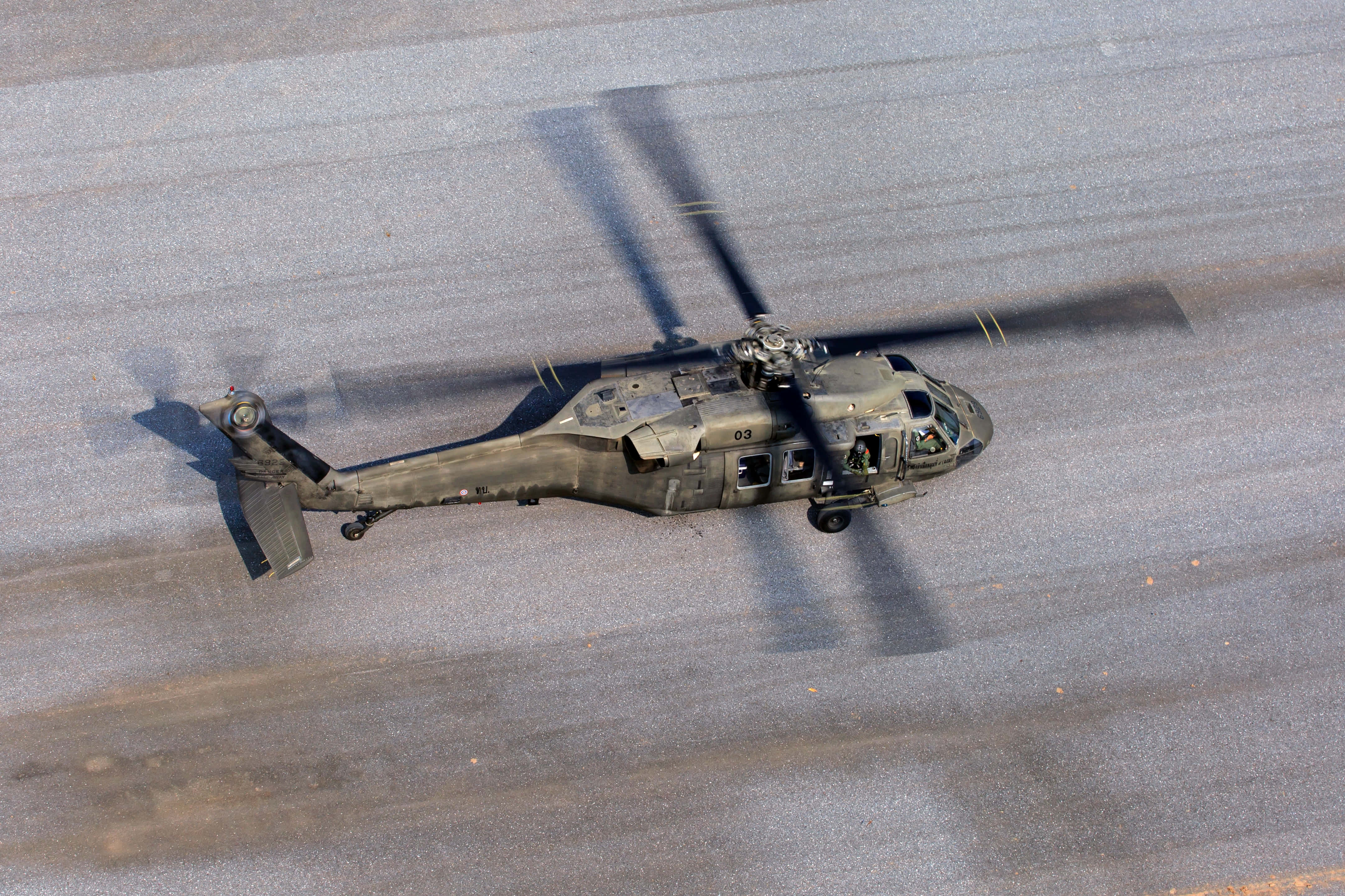 Helicopter 桌布 壁紙 — 一架迷彩軍用直升機停在柏油停機坪上，旋翼槳葉投下長長的陰影。