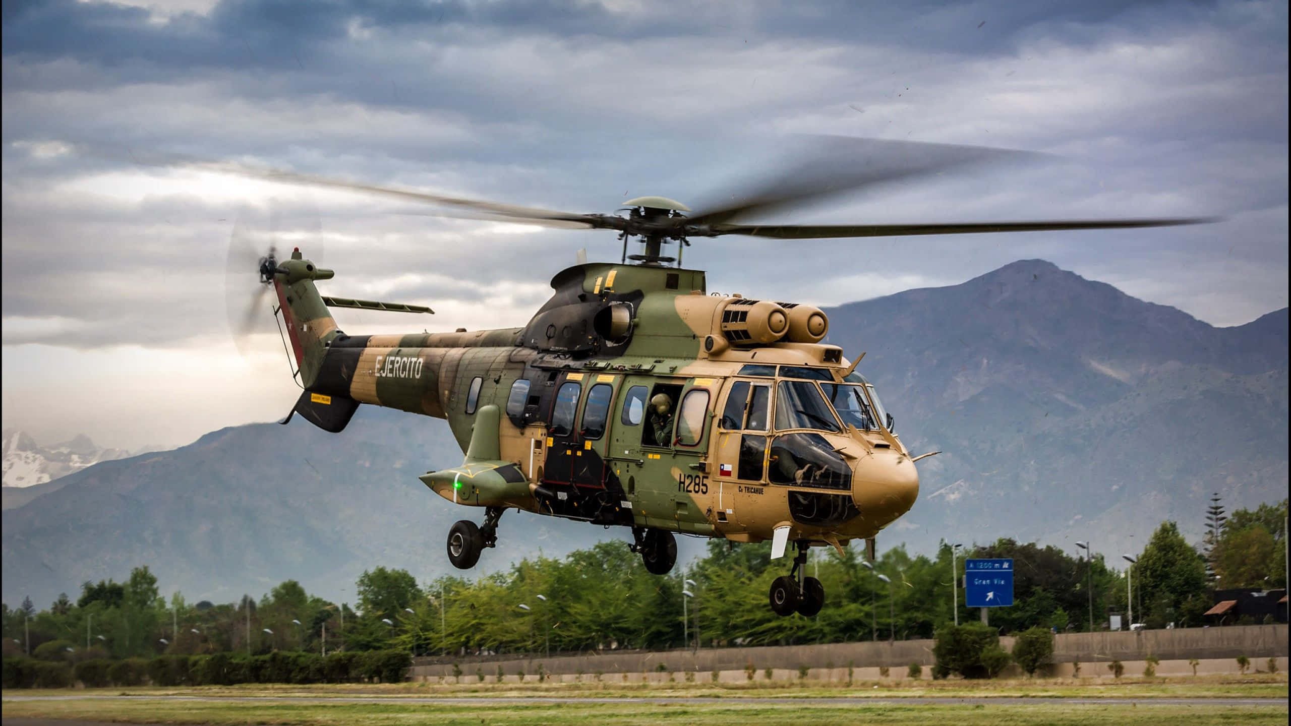 Helicopter 桌布 壁紙 — 一架迷彩軍用直升機在群山和陰天背景下起飛。