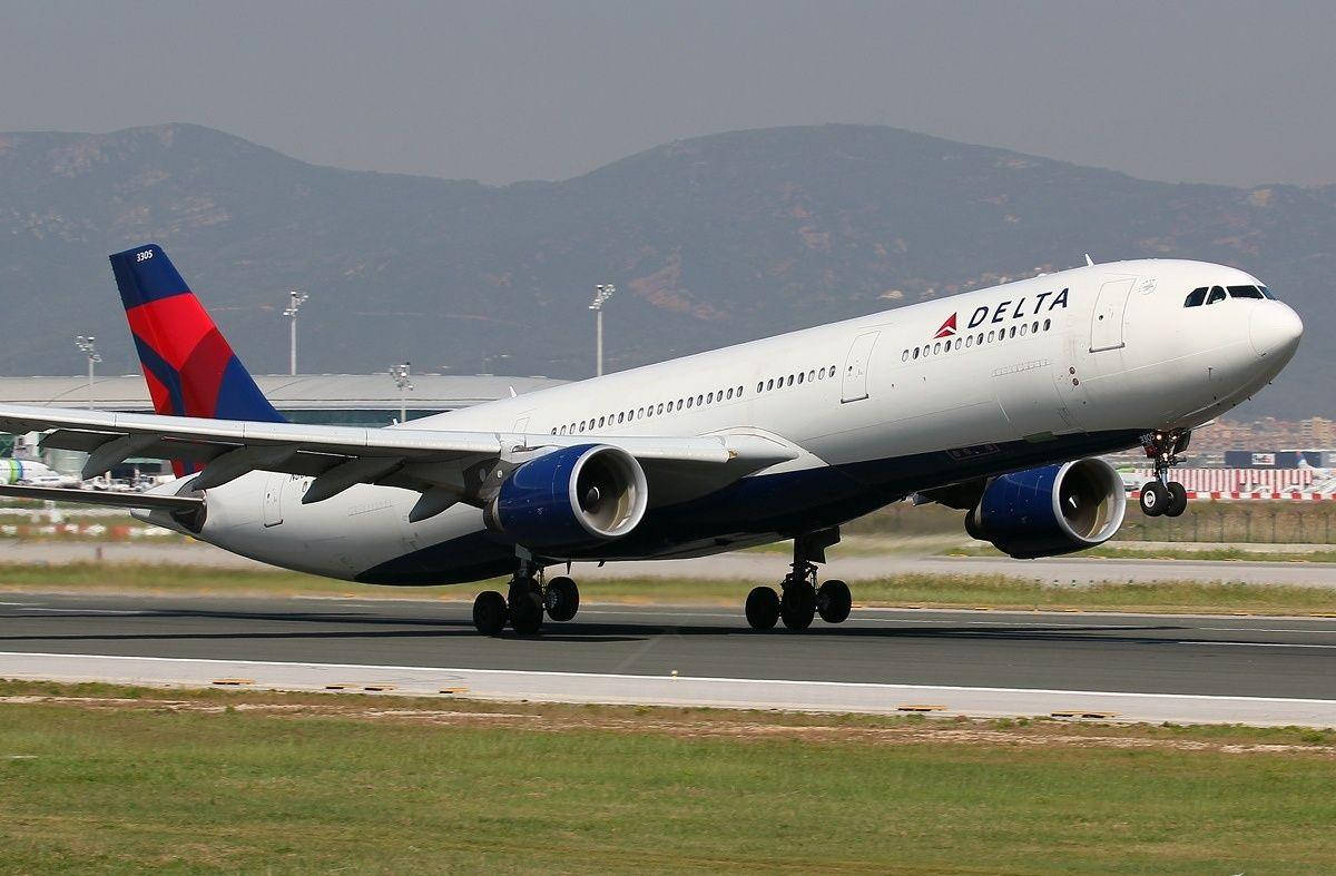 Plane 桌布 壁紙 — 一架達美航空空中巴士A330在晴朗天空下，背景有朦朧山巒，降落在跑道上。