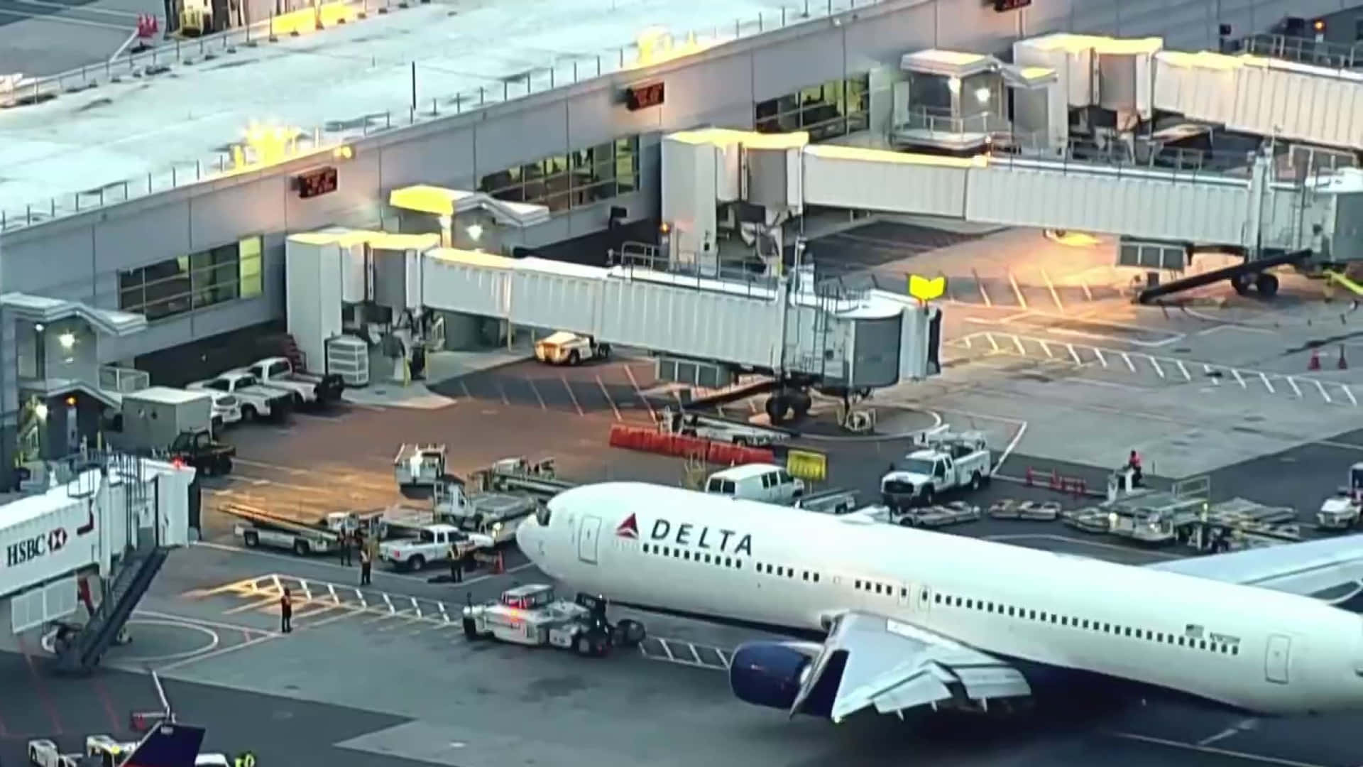 桌布 壁紙 — 一架達美航空飛機停在機場閘口，可以看到空橋和地面車輛在人工燈光下。