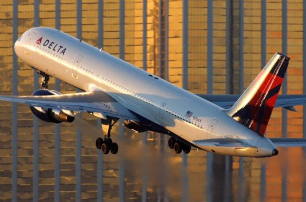 Plane 桌布 壁紙 — 一架達美航空飛機在金色夕陽映照高樓大廈的背景下起飛。
