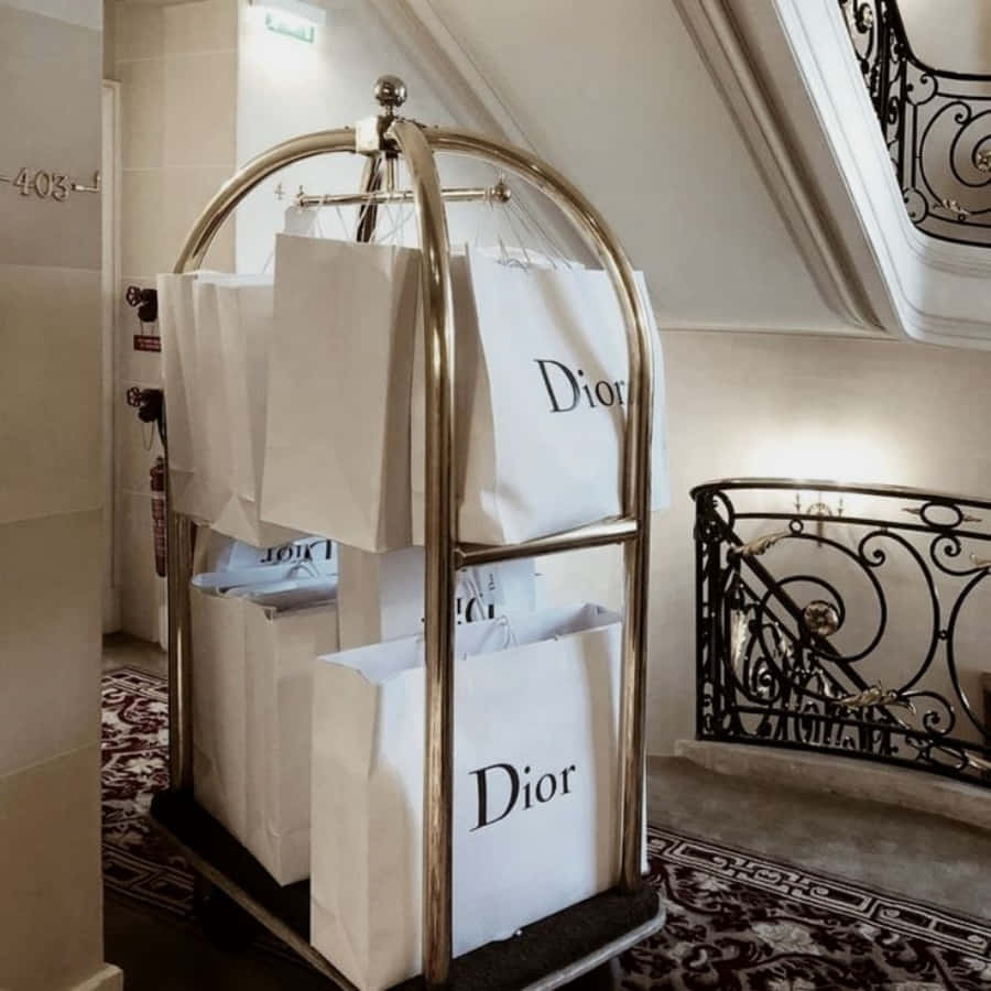 Dior 動態 桌布 壁紙 — 一架金色酒店行李車載滿白色Dior購物袋，立在華麗酒店走廊的裝飾樓梯旁。