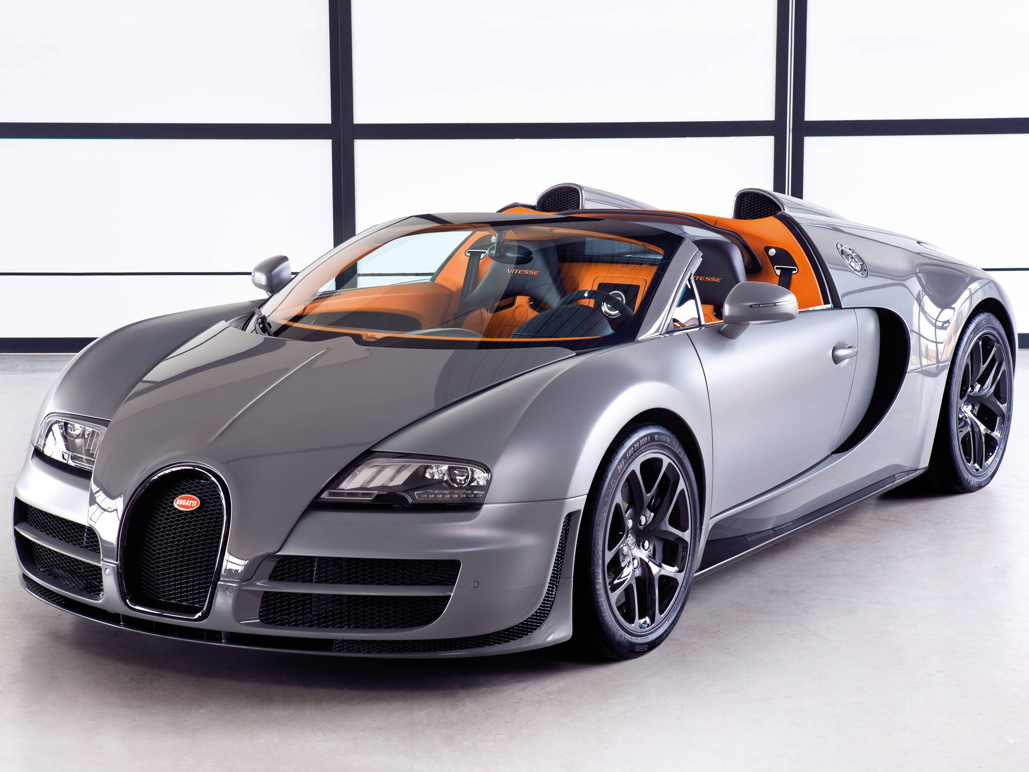 bugatti iPhone 桌布 壁紙 — 一架銀色布加迪威龍跑車，配橙色內裝，停放在簡約的白色工作室空間內。