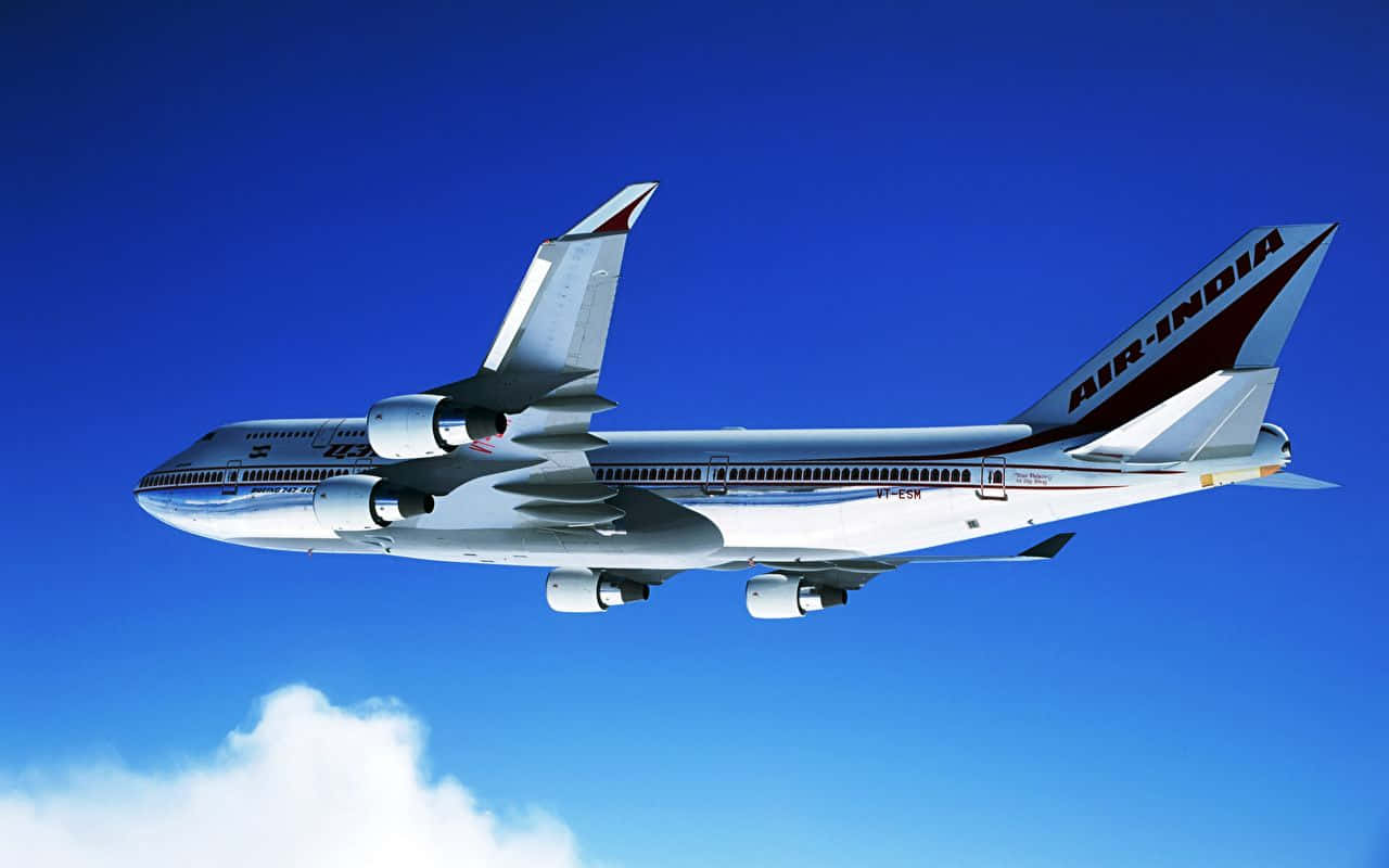 飛機 桌布 壁紙 — 一架銀色的印度航空波音747在晴朗的藍天中翱翔，下方有一朵白雲。