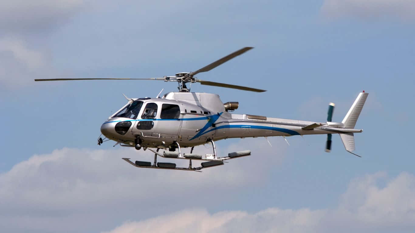 1366x768 Helicopters 桌布 壁紙 — 一架銀藍色帶滑雪板的直升機在部分多雲的藍天中飛行。