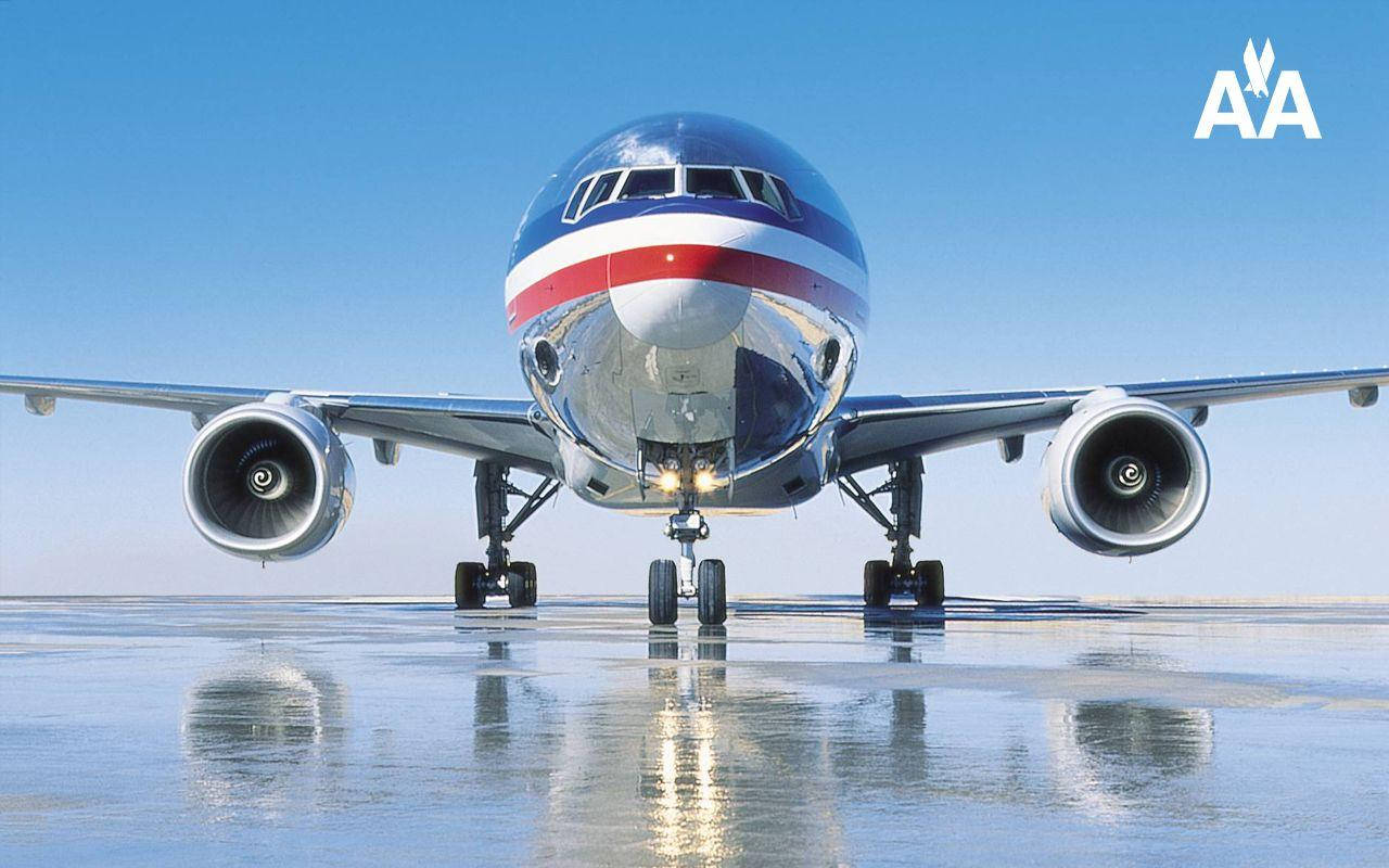 Airlines 桌布 壁紙 — 一架閃亮的美國航空噴射客機在晴朗藍天下，面向前方停在濕滑跑道上，倒影完美。