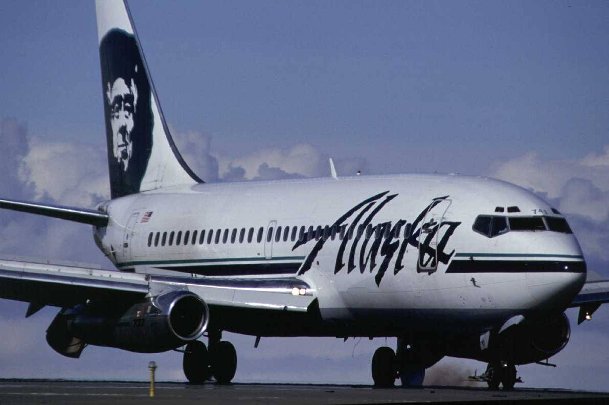  壁紙 — 一架阿拉斯加航空的波音737停在停機坪上，天空部分多雲，機尾有獨特的面部標誌。