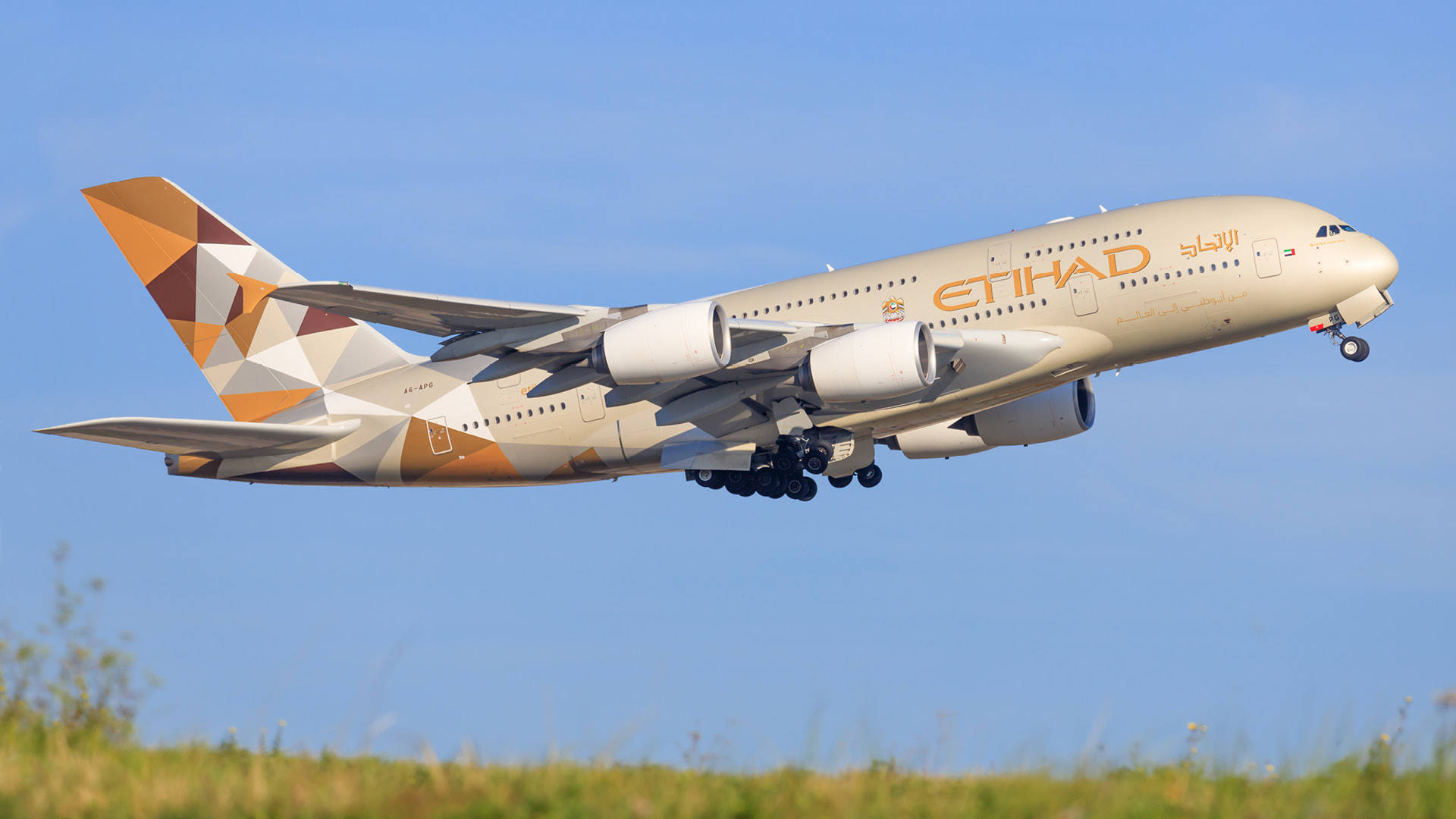 飛機 桌布 壁紙 — 一架阿提哈德航空的空中巴士A380，採用幾何圖案塗裝，在草地上方晴朗的藍天中攀升。