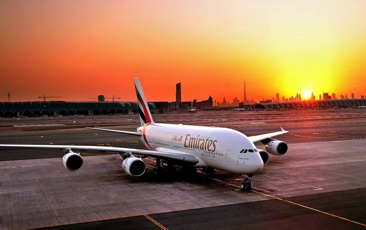 阿聯酋航空A380飛機在停機坪上，背景為夕陽和城市天際線 — 風景動畫 壁紙