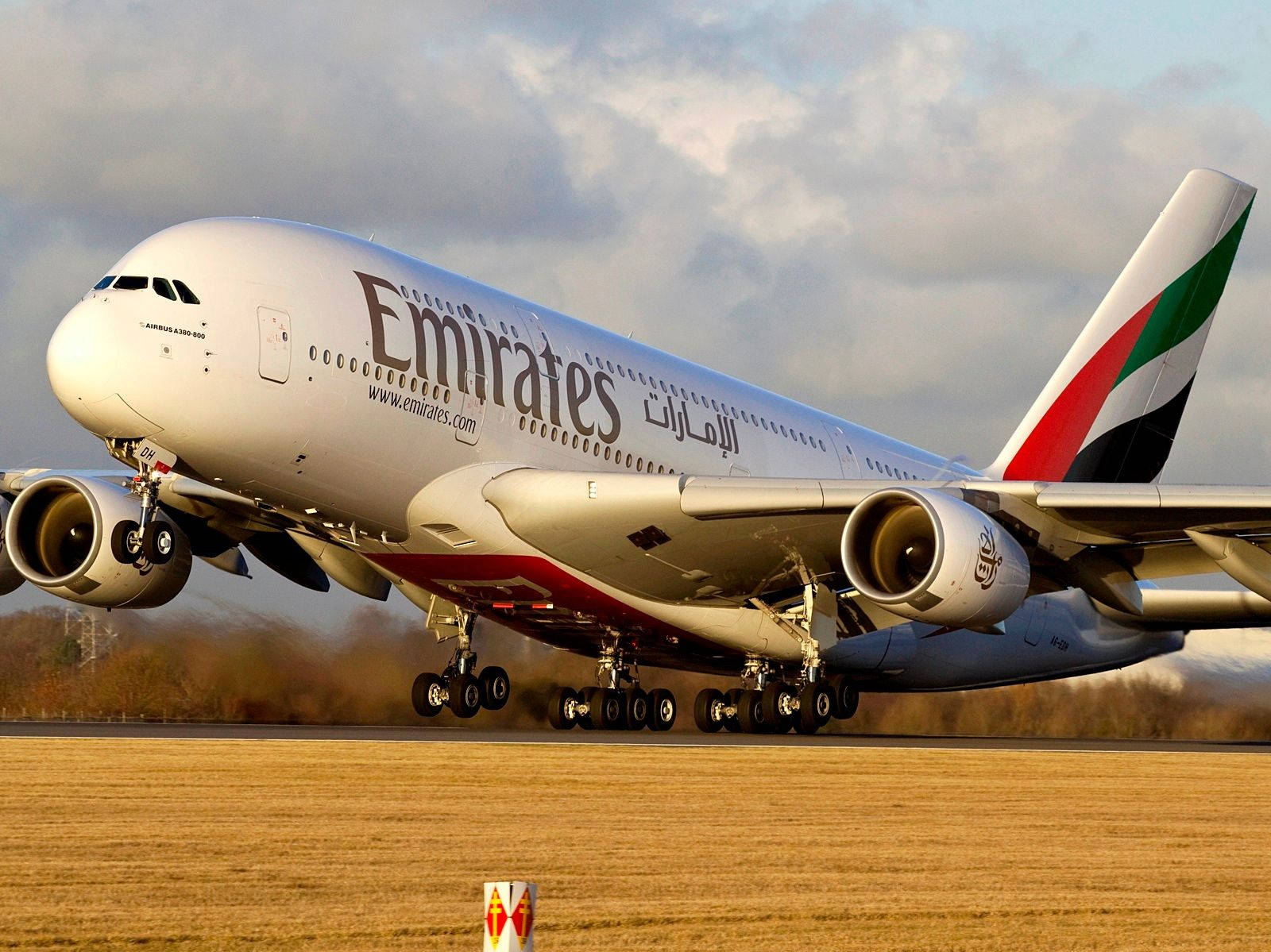 飛機 桌布 壁紙 — 一架阿聯酋航空空中巴士A380在多雲的天空下，起落架伸出，從跑道起飛。