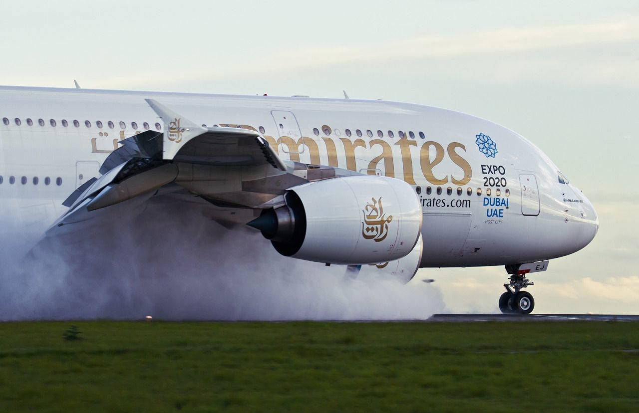 Airport 桌布 壁紙 — 一架阿聯酋航空空中巴士A380在蒼白天空下，於草地跑道降落，輪胎冒出濃煙。