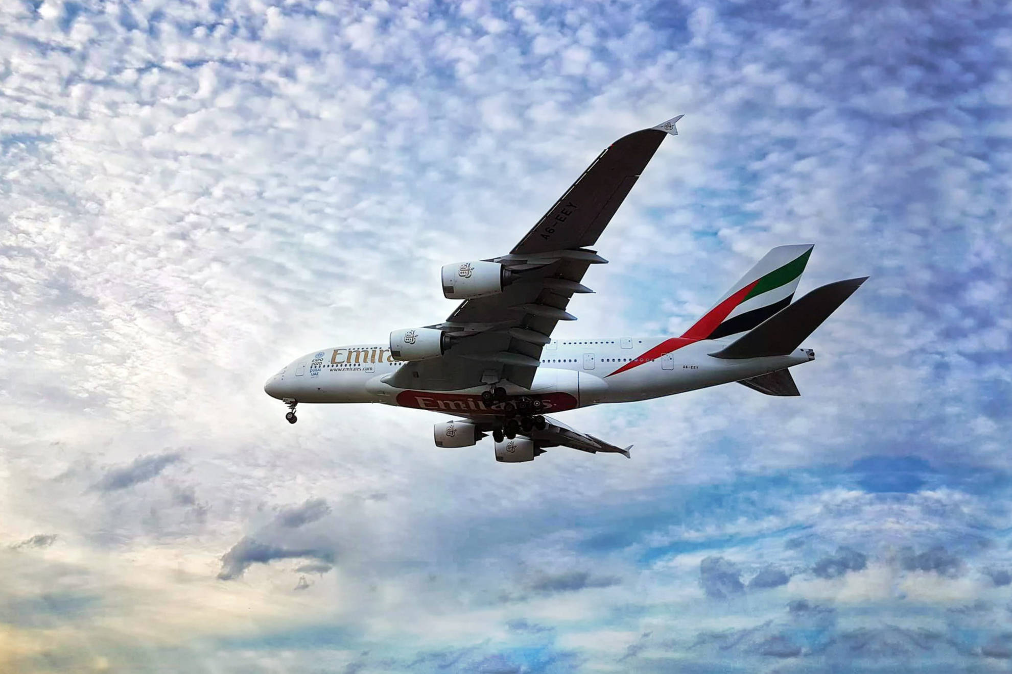 Arab 桌布 壁紙 — 一架阿聯酋航空空中巴士A380在充滿散落白雲的鮮豔藍天中翱翔。