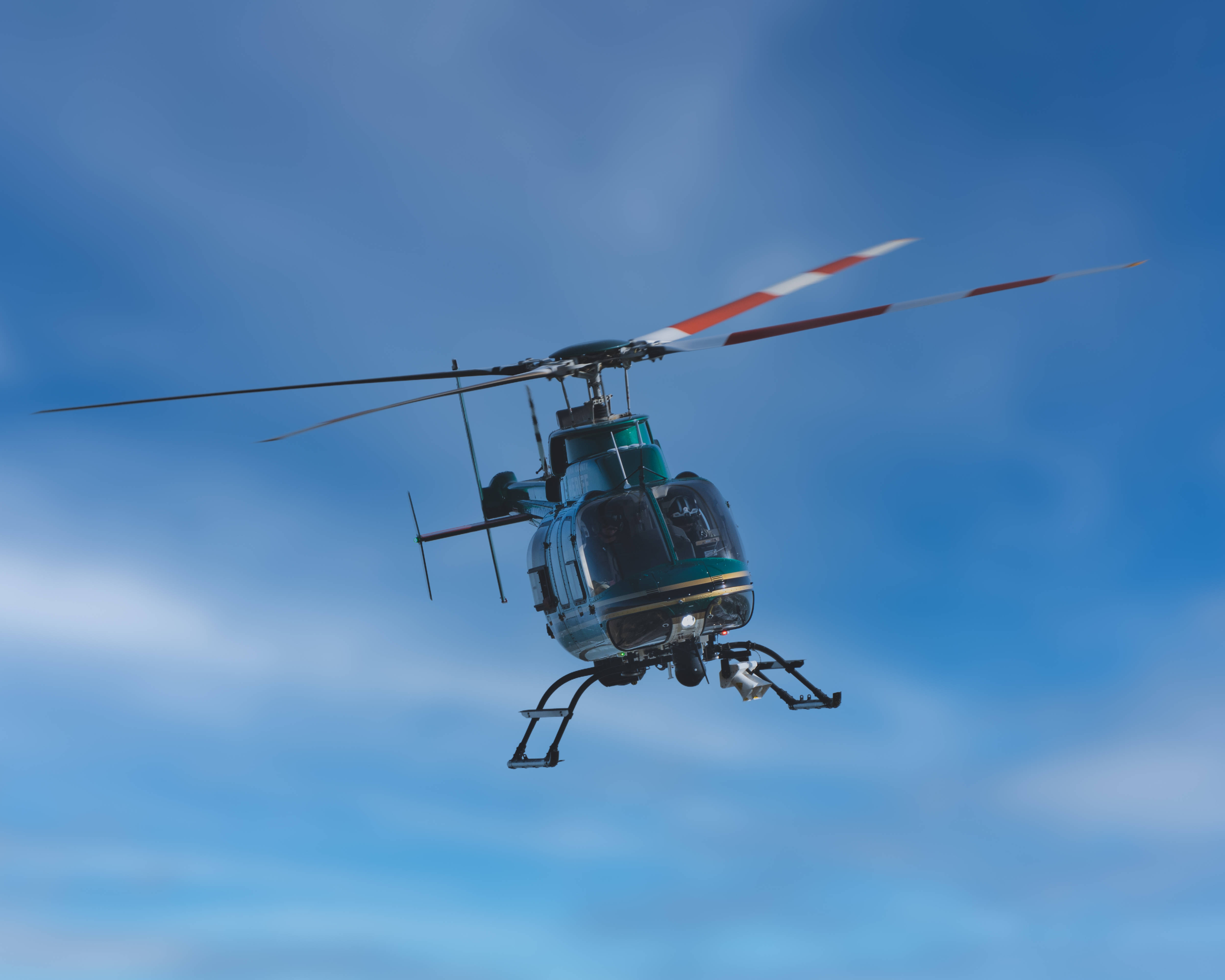 Helicopter 桌布 壁紙 — 一架青綠色直升機帶有紅白條紋的旋翼，在晴朗的藍天中翱翔，伴隨著縷縷白雲。