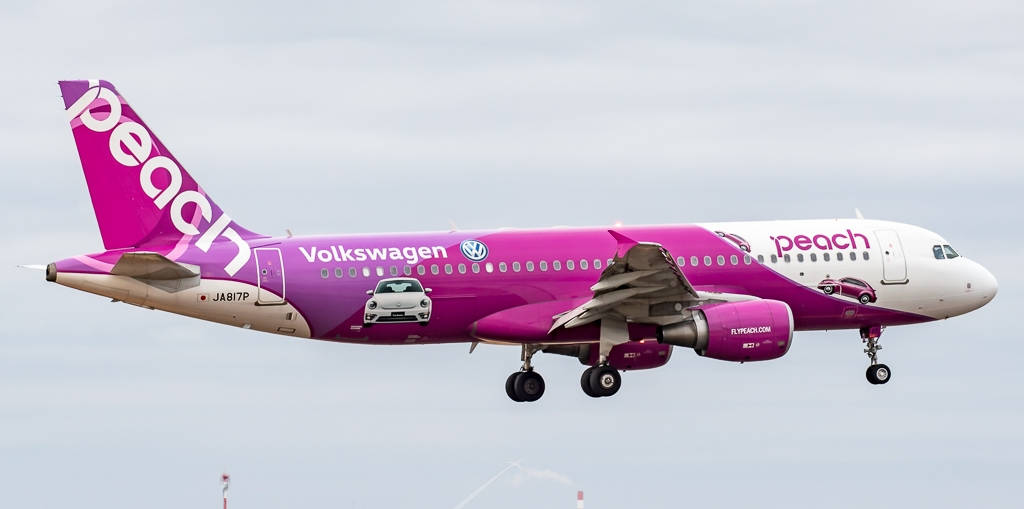 Blue Sky 桌布 壁紙 — 一架鮮粉紅色的Peach Airlines空中巴士A320，帶有Volkswagen品牌和汽車圖案，在多雲的天空中飛行。