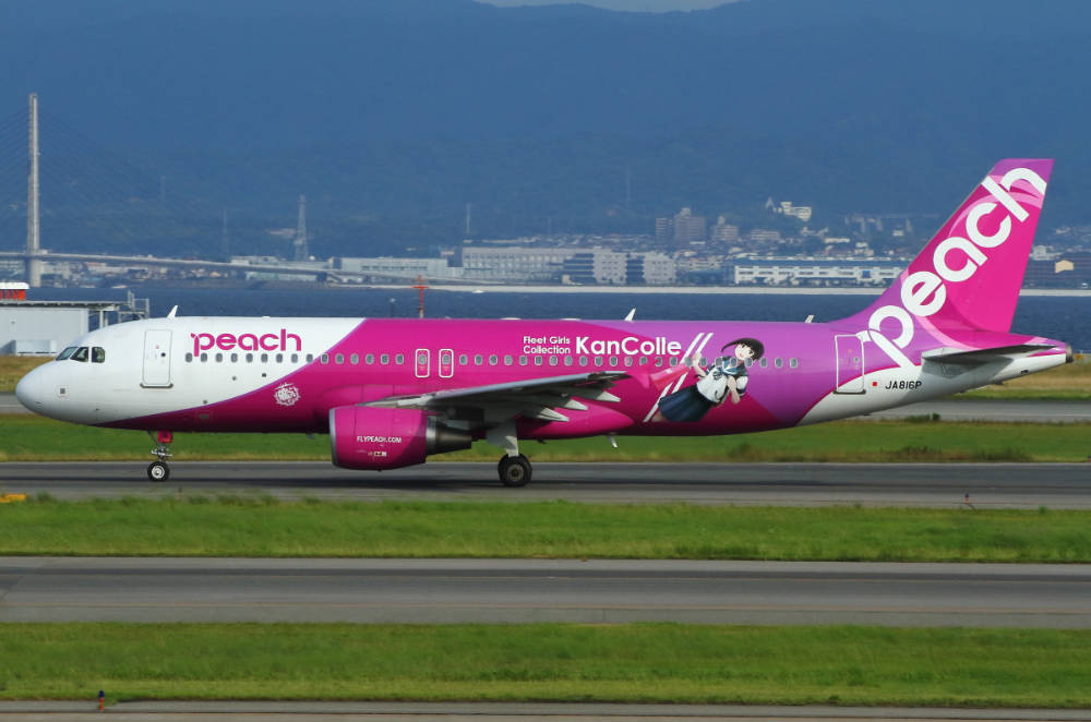 飛機 桌布 壁紙 — 一架鮮粉紅色的Peach Airlines飛機帶有艦Colle動漫塗裝，在跑道滑行，背景是朦朧的山巒。