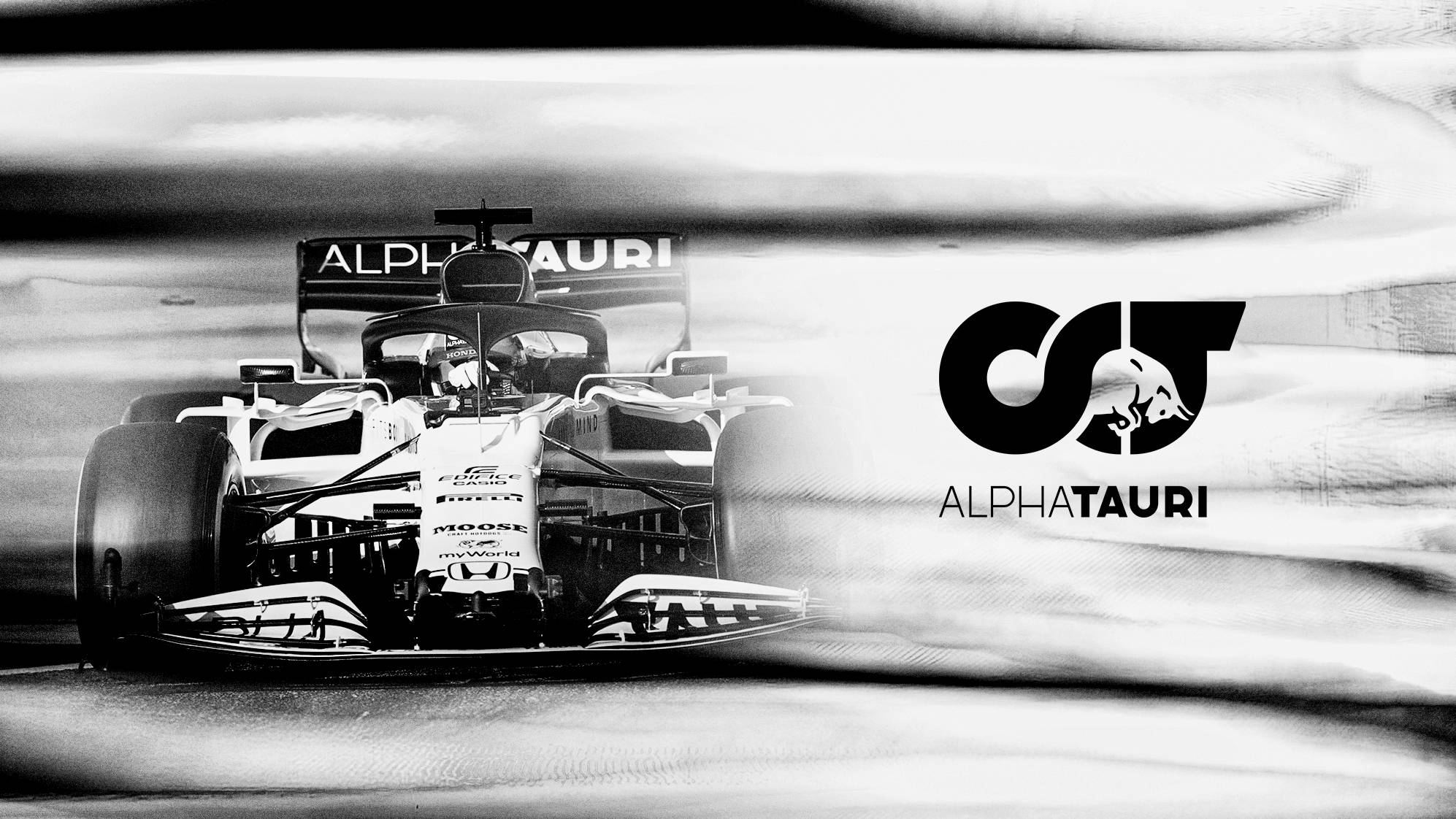 F1 桌布 壁紙 — 一架黑白高速一級方程式AlphaTauri賽車在賽道上疾馳而過，帶有動態模糊痕跡。