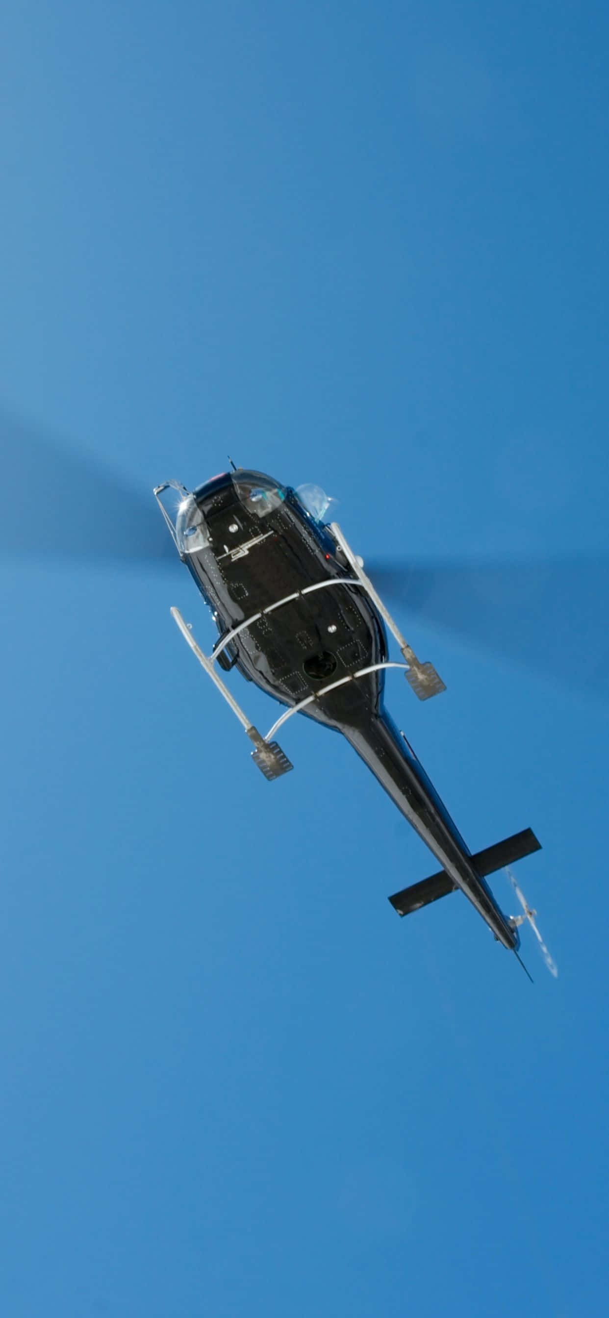 iPhone Xs Max Helicopters 桌布 壁紙 — 一架黑色直升機在廣闊清澈的藍天中翱翔，旋翼轉動。