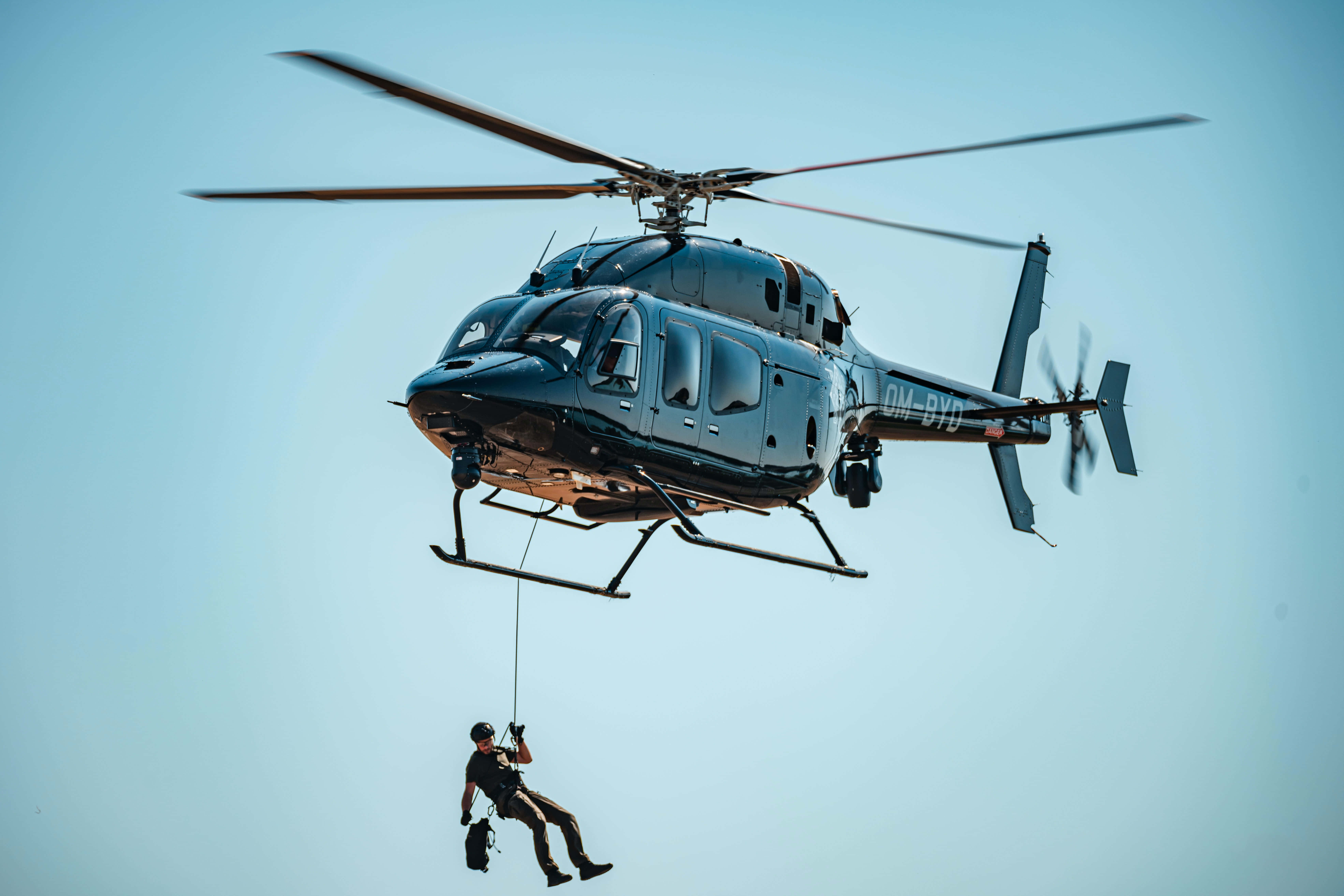 Helicopter 桌布 壁紙 — 一架黑色直升機在晴朗的藍天中盤旋，下方有人沿繩索垂降。