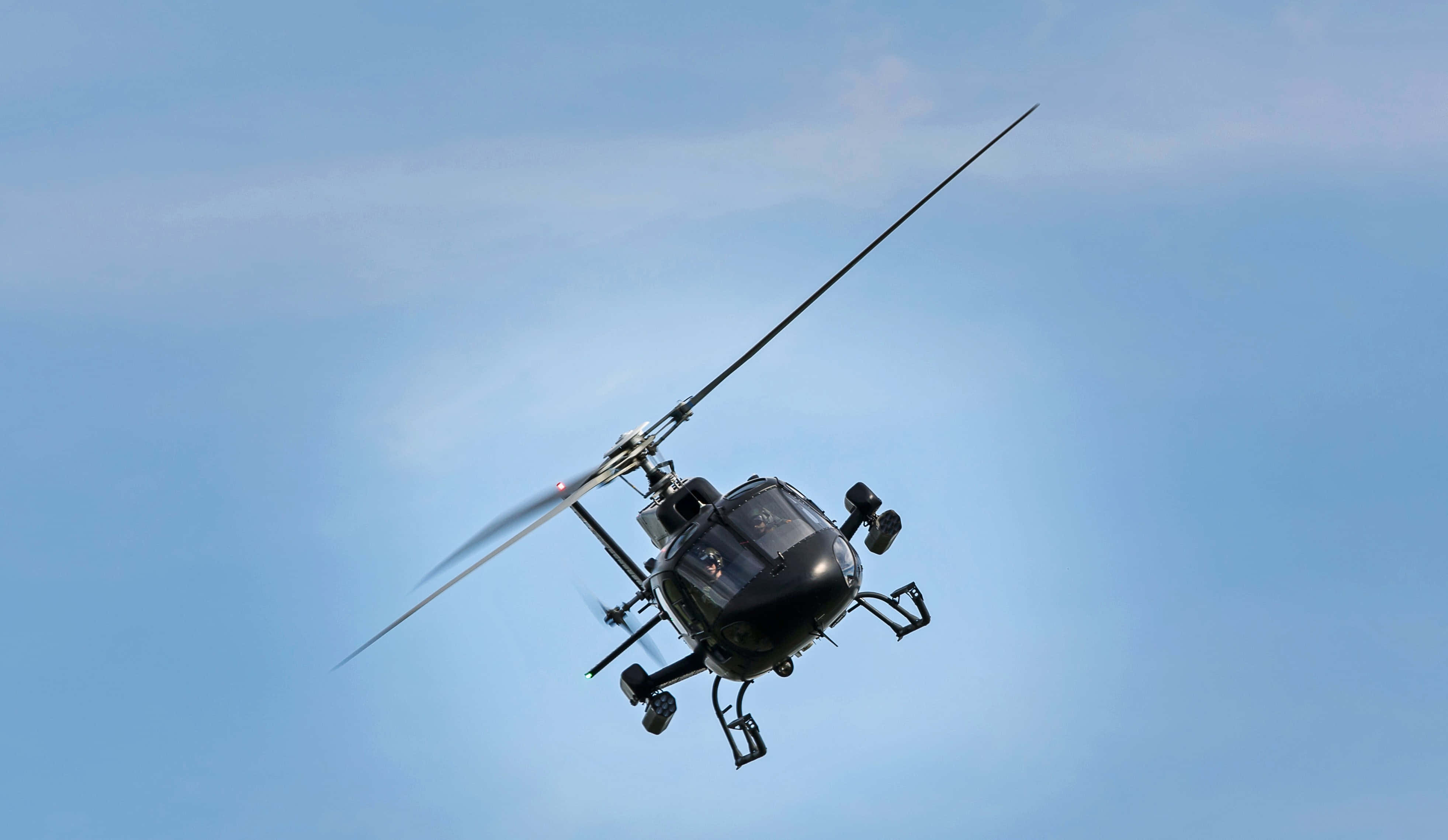 Helicopters 桌布 壁紙 — 一架黑色直升機在晴朗的藍天中翱翔，旋翼快速轉動。