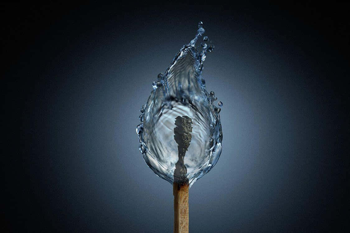 Conceptual Art 桌布 壁紙 — 一根火柴，其燃燒的頭部周圍有水滴在半空中凍結，背景為深色漸變。
