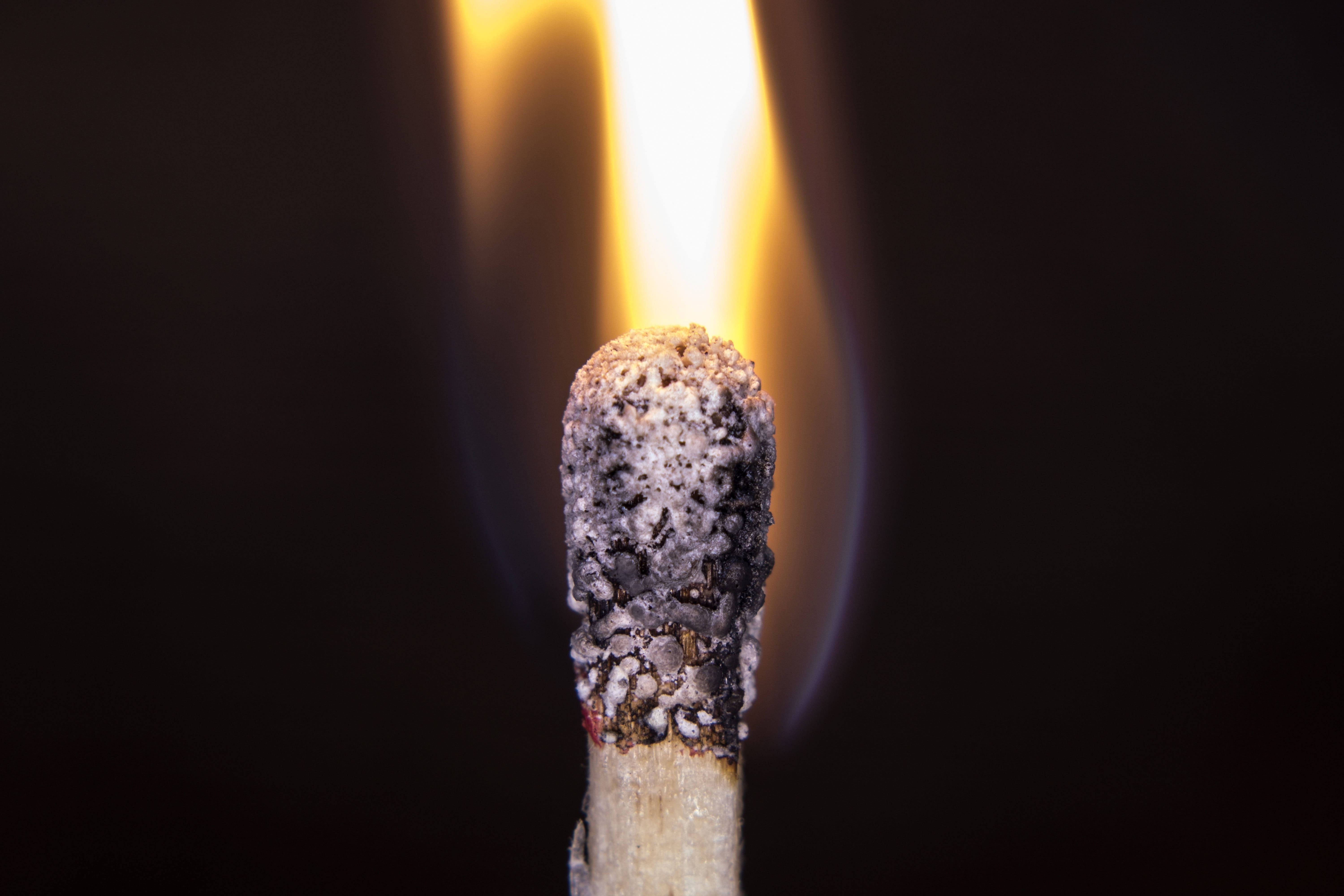 Temperature 桌布 壁紙 — 一根燃燒中的火柴特寫，在黑暗背景上發出明亮的黃色火焰。