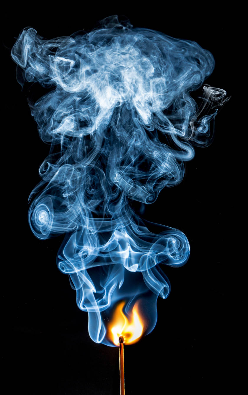 Flames 桌布 壁紙 — 一根燃燒的火柴在純黑背景上散發出鮮豔的藍色煙霧，營造出空靈而短暫的視覺效果。