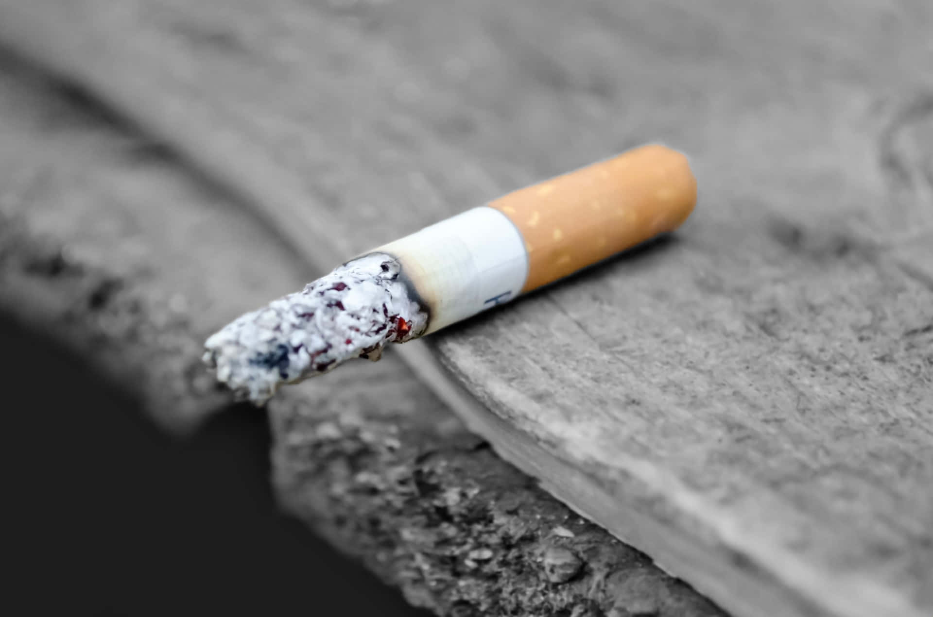cigarettes 桌布 壁紙 — 一根燒過的香煙放在粗糙的混凝土邊緣上，景深較淺。