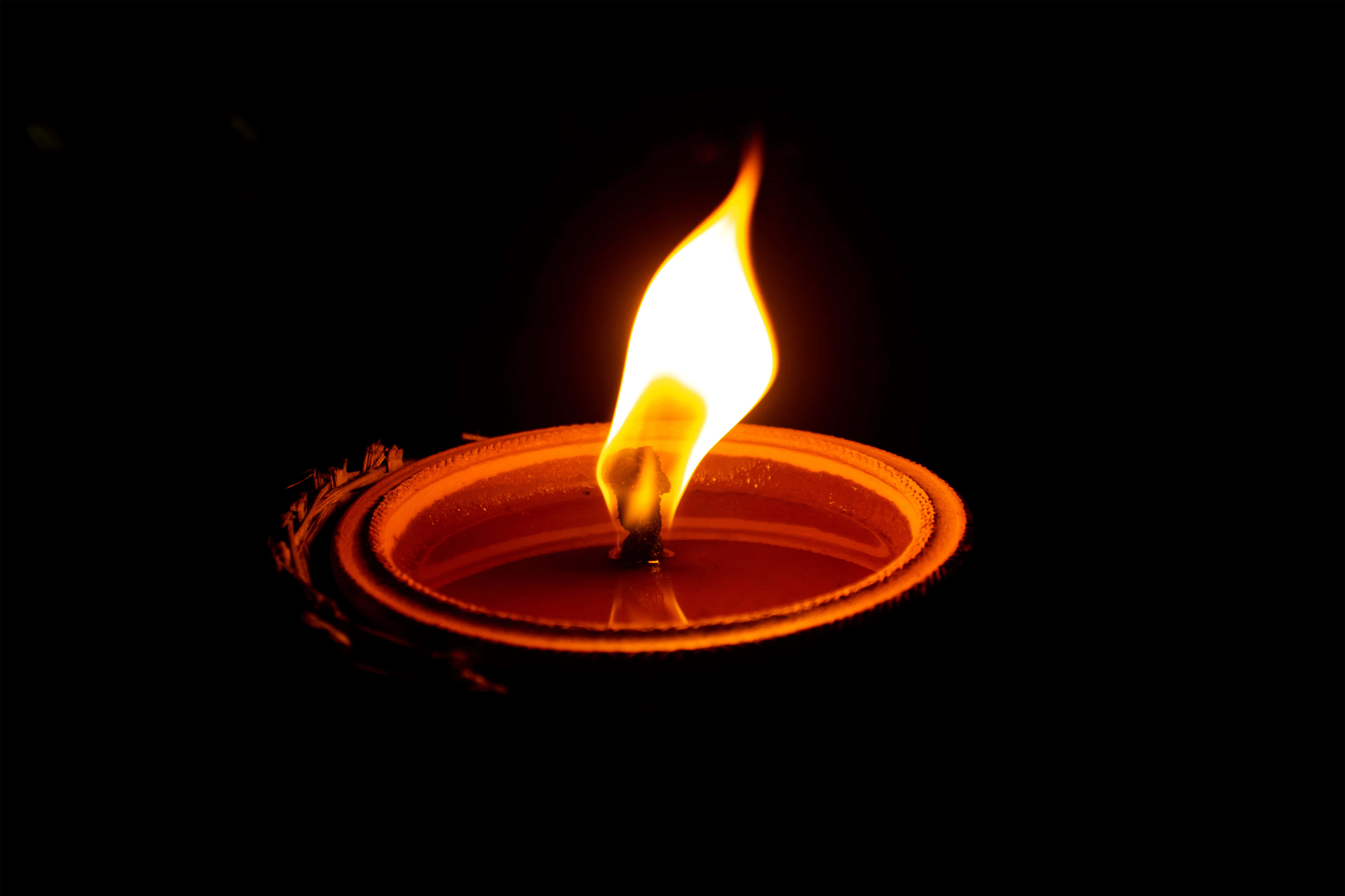 Memorial 桌布 壁紙 — 一根蠟燭的火焰在漆黑的背景中溫暖地搖曳，散發出柔和的橙色光芒。