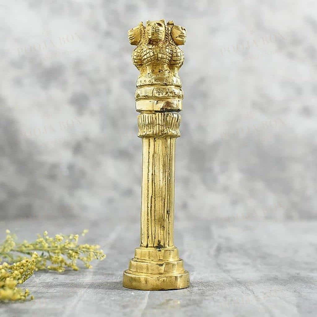 statue 桌布 壁紙 — 一根金色華麗的柱子，頂部有三個獅子頭，立在大理石表面上，旁邊是精緻的黃色花朵。