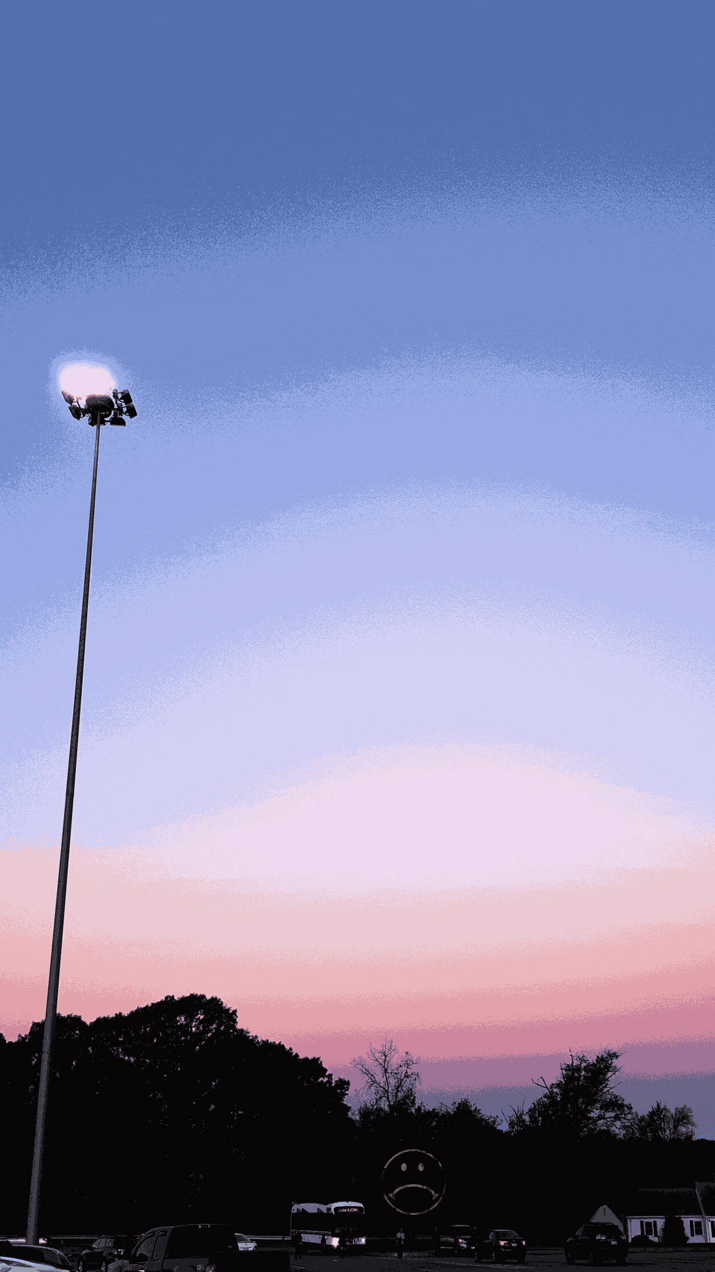粉紅色系 iPhone 桌布 壁紙 — 一根高大的體育場燈柱聳立在暮色天空下，天空塗上柔和的粉紅和藍色調，下方有剪影般的樹木和汽車。