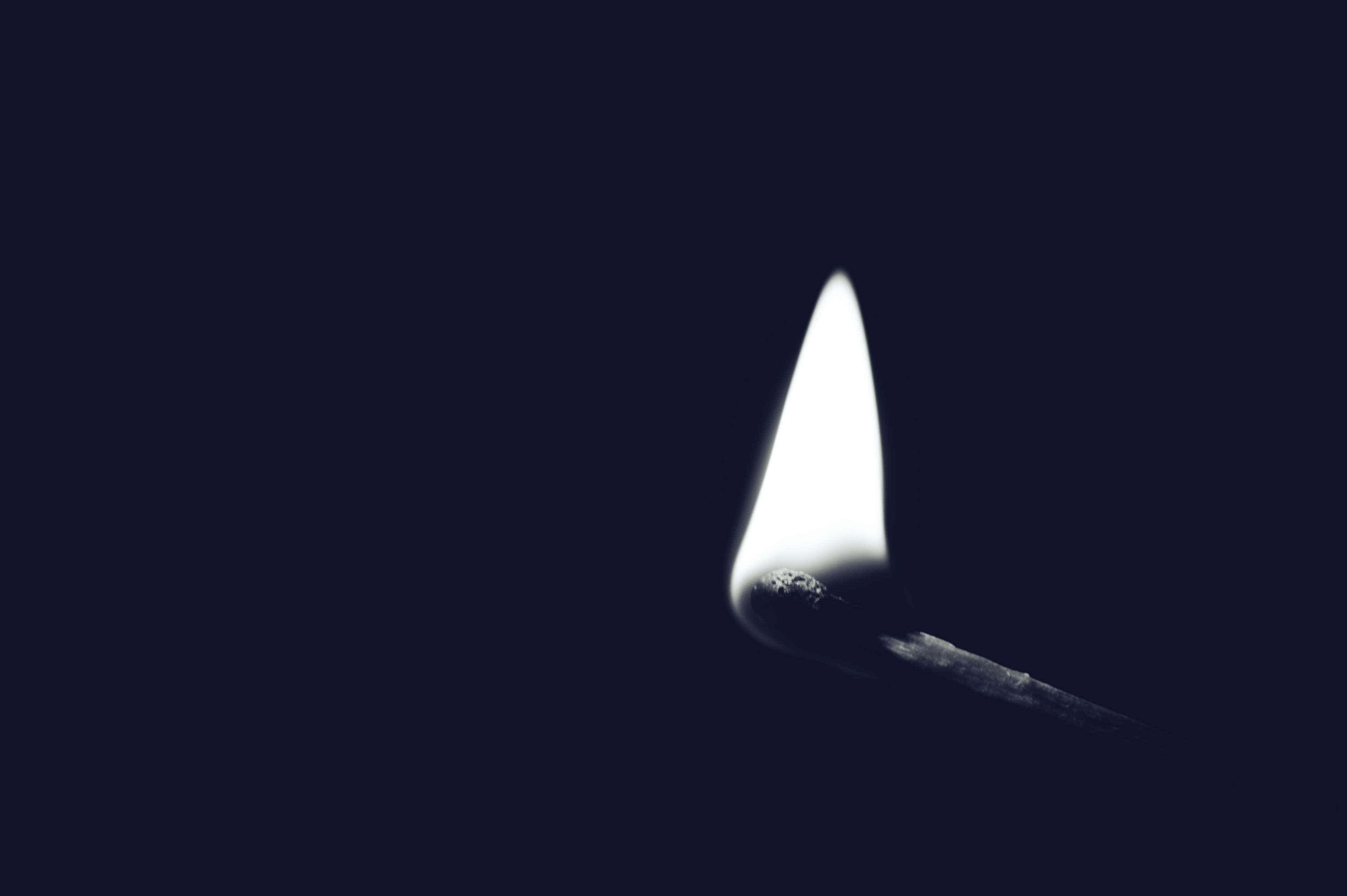 Lit iPhone 桌布 壁紙 — 一根點燃的火柴在深藍色背景上發出明亮的白色火焰。