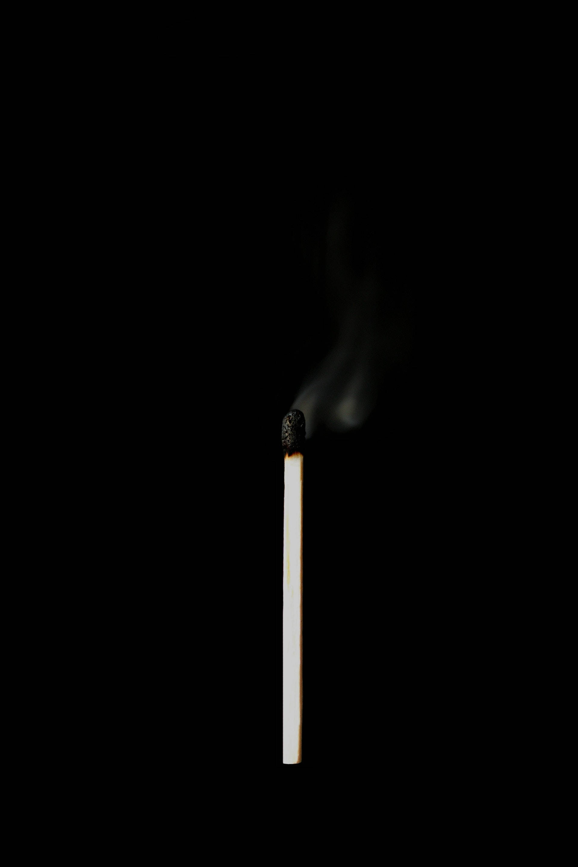 Black Phone 桌布 壁紙 — 一根點燃的火柴在漆黑背景中散發出溫暖的光芒，縷縷煙霧向上盤旋。