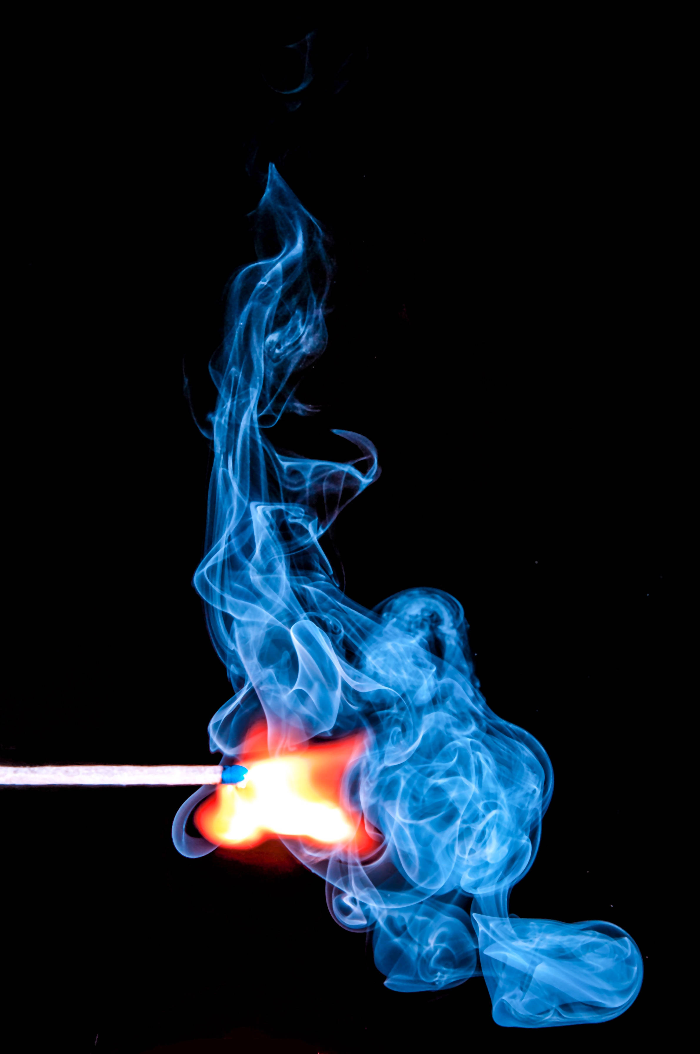 火焰動畫 桌布 壁紙 — 一根點燃的火柴在純黑背景上投射出鮮豔的橙色火焰和旋轉的藍色煙霧。