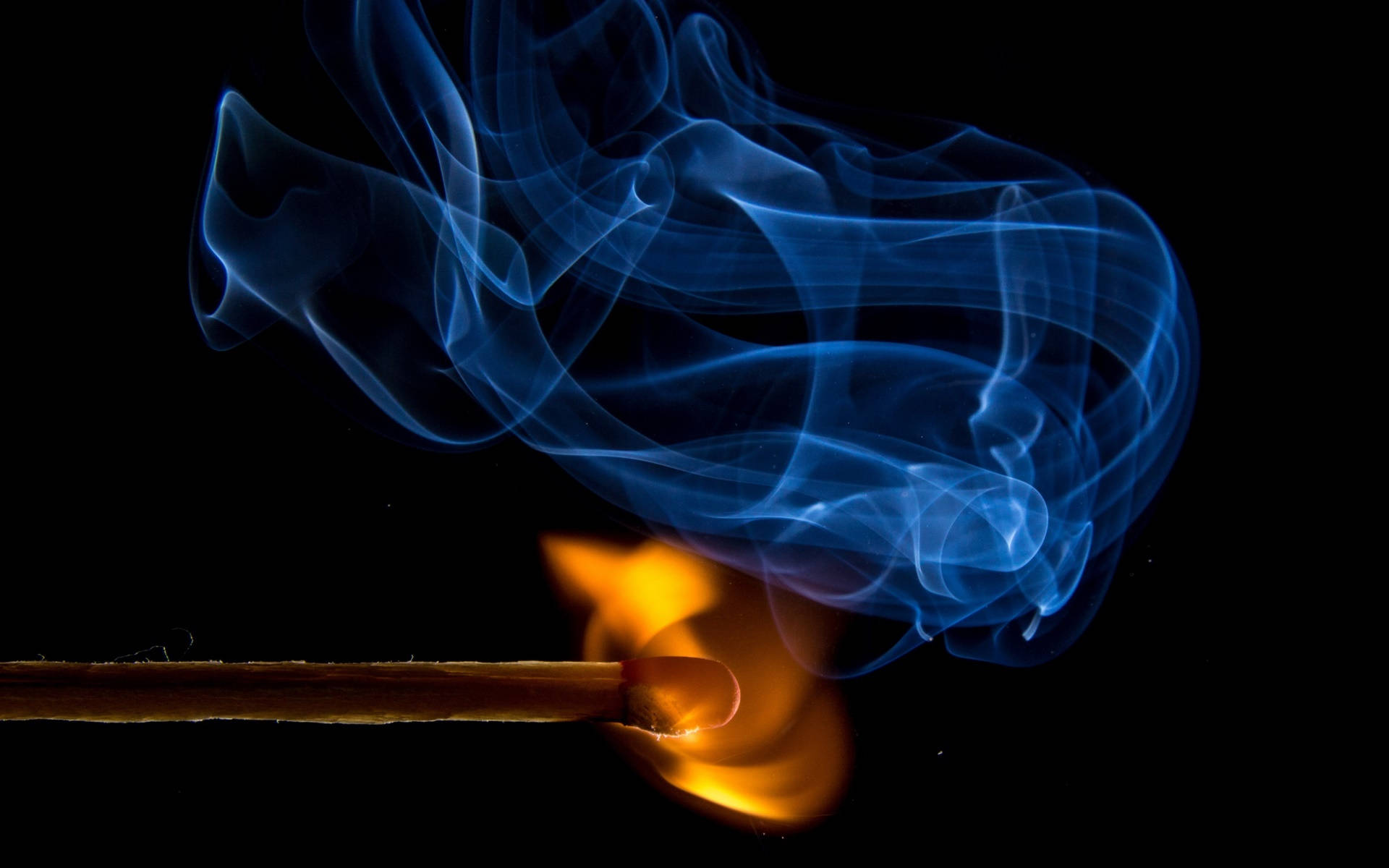 火焰動畫 桌布 壁紙 — 一根點燃的火柴在黑色背景上投射出鮮豔的橙色火焰，藍色煙霧優雅地盤旋上升。