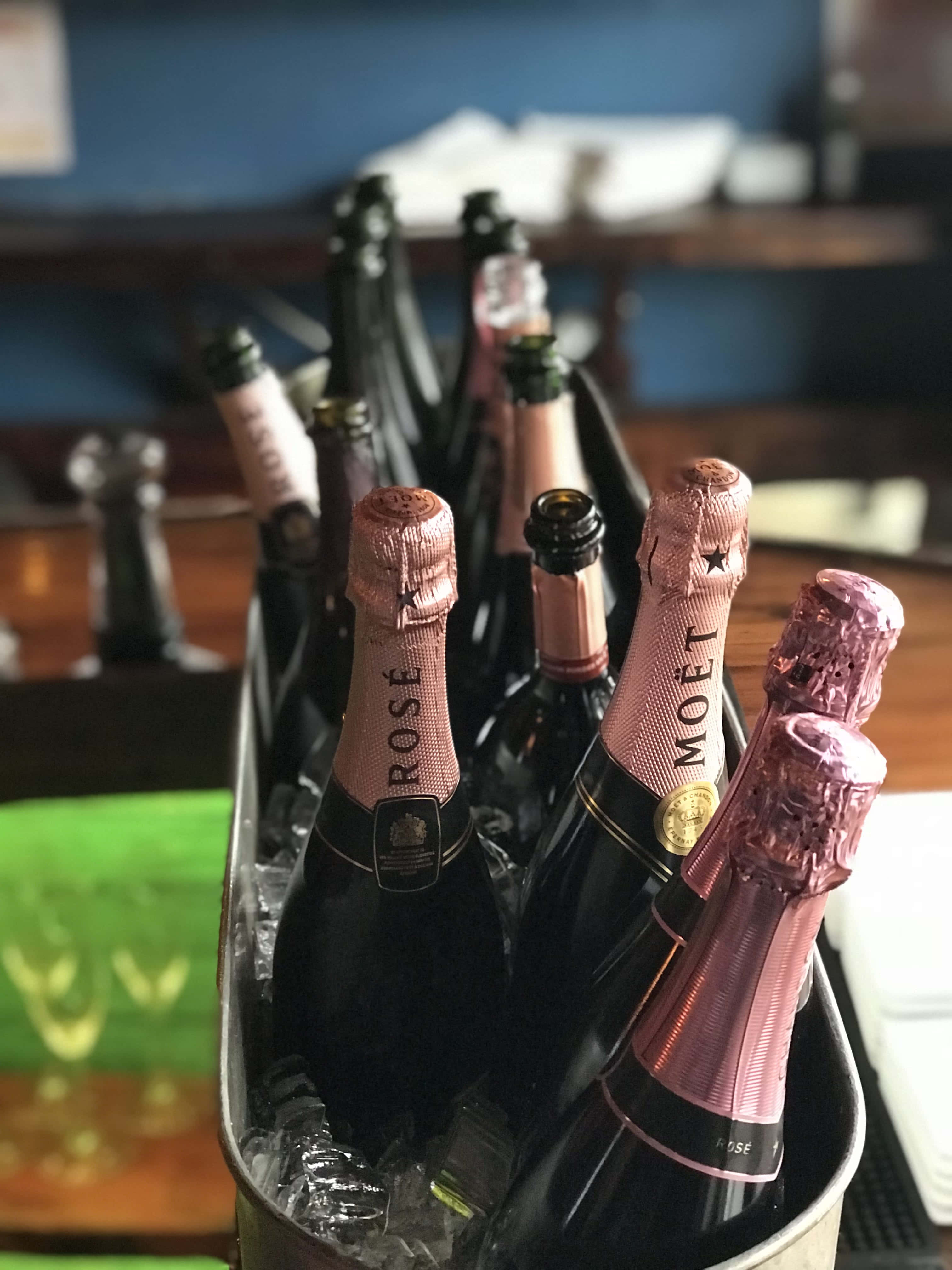 Pink Champagne 桌布 壁紙 — 一桶冰鎮 Moët & Chandon Rosé 香檳酒瓶放在酒吧檯上的冰塊中。