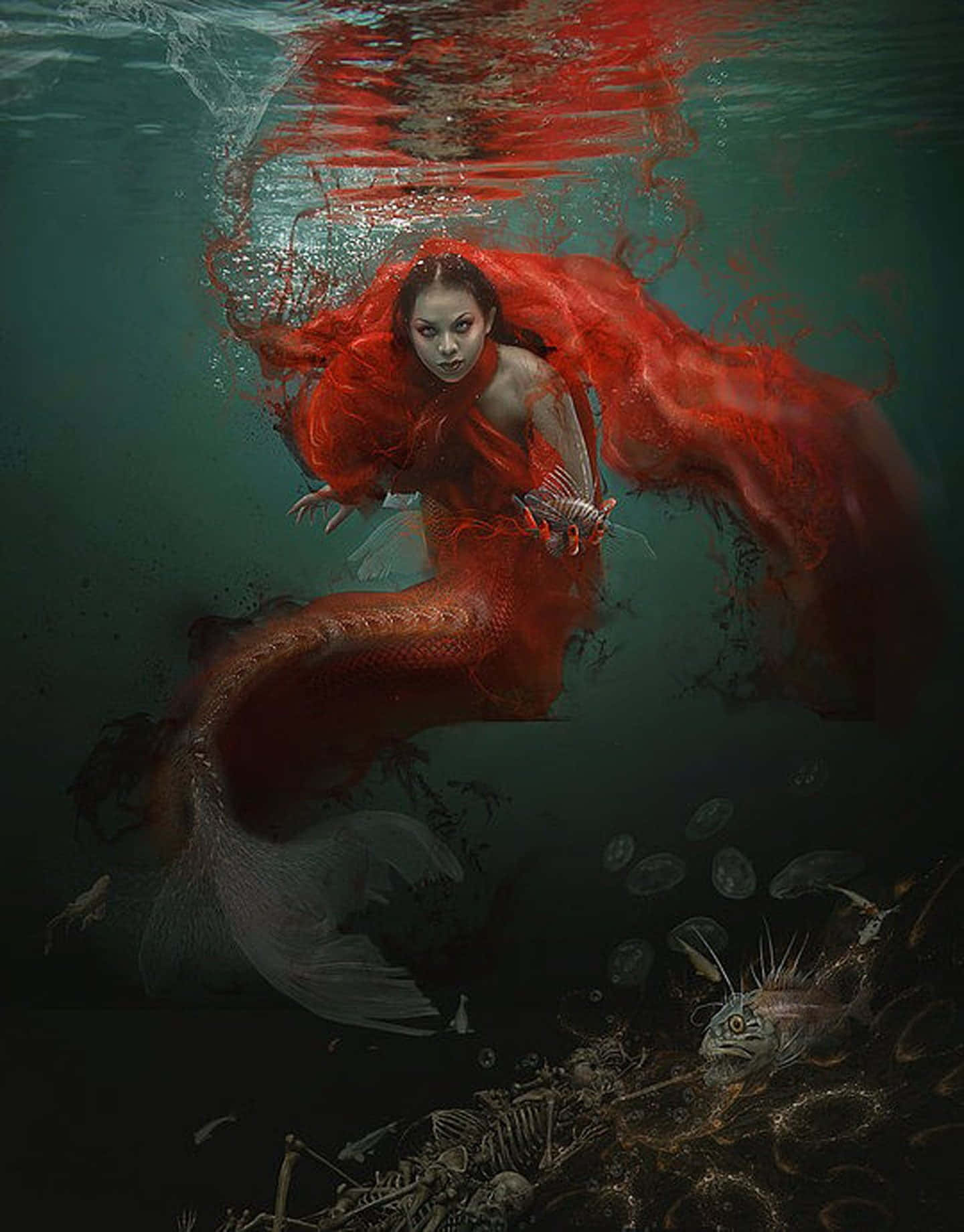 美人魚 桌布 壁紙 — 一條令人毛骨悚然的美人魚，擁有飄逸的紅髮和尾巴，在渾濁的綠色海水中滑行，下方是魚骨和水母的墳場。