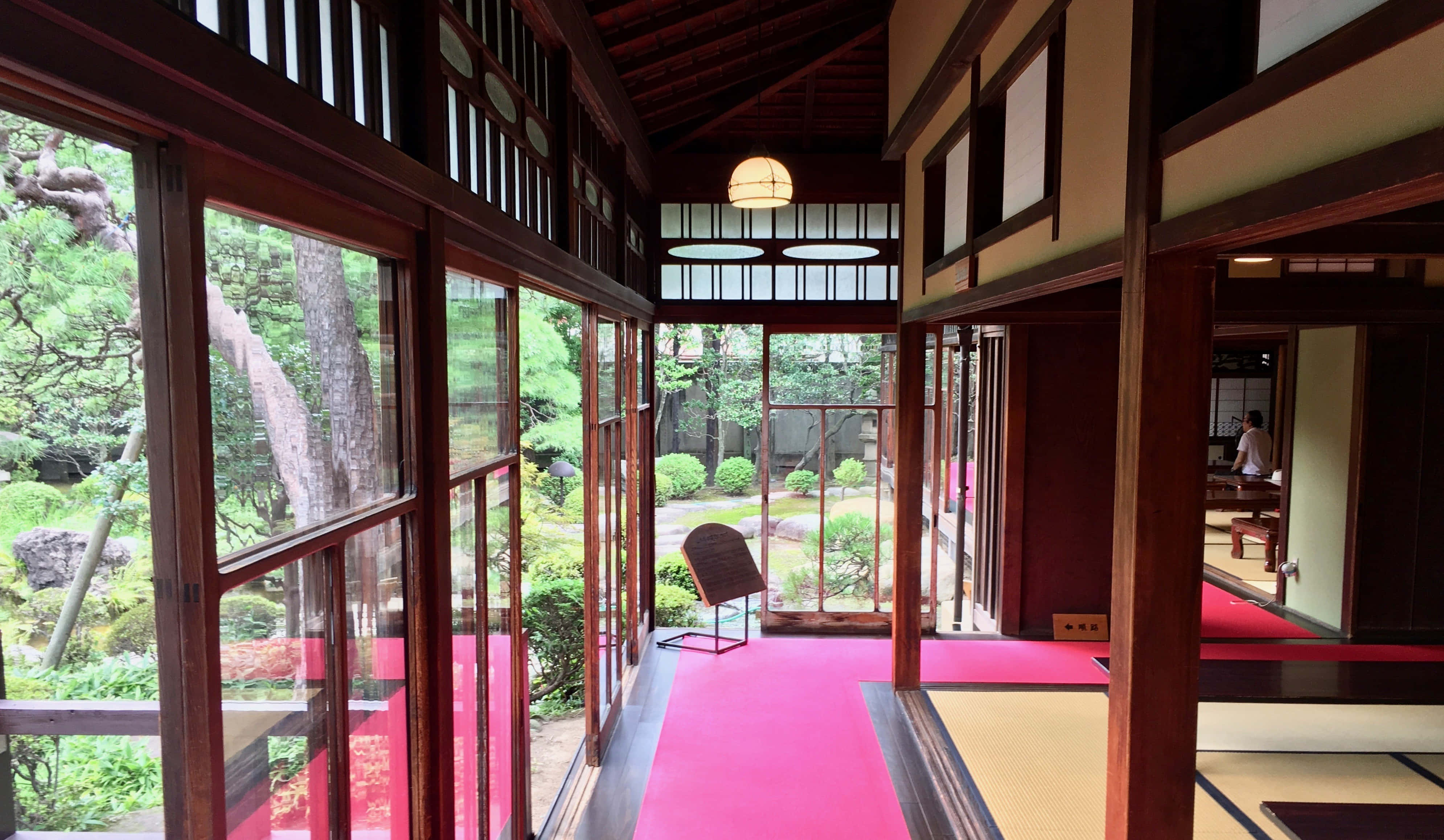 Tokyo Japan 桌布 壁紙 — 一條傳統日式走廊，有木樑和拉門，通向一個沐浴在自然光中的寧靜苔蘚花園。