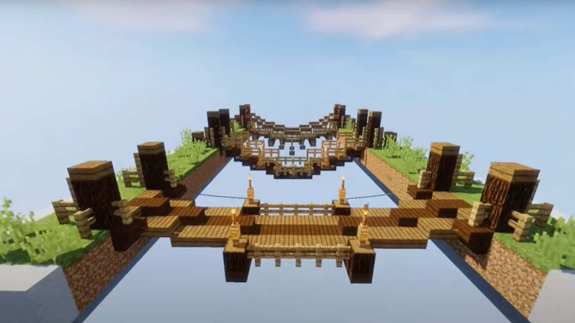 Minecraft Bridges 桌布 壁紙 — 一條像素風格的木橋，上面有火炬，橫跨Minecraft景觀中平靜的河流，天空清澈湛藍。