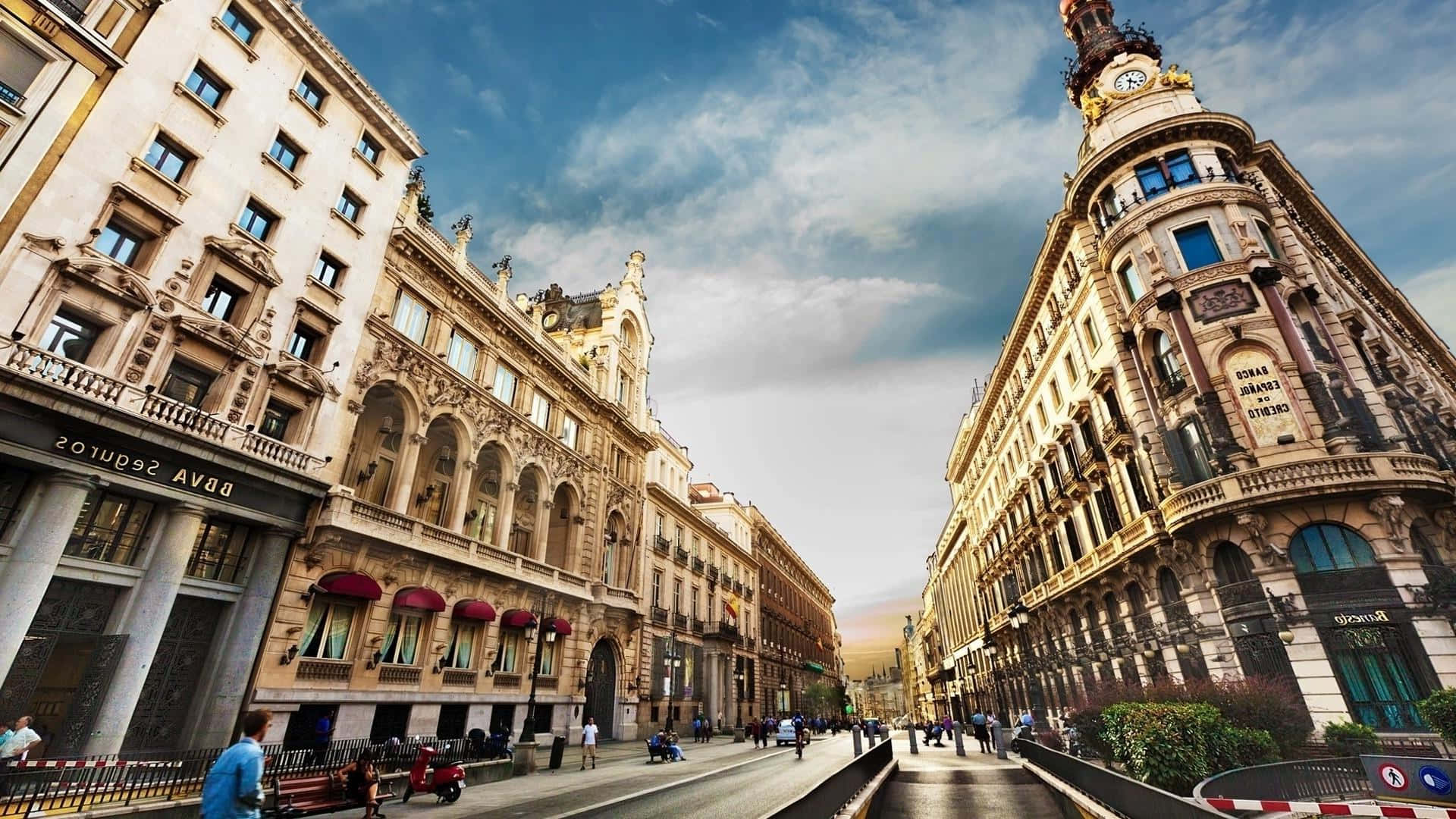 Barcelona 桌布 壁紙 — 一條充滿活力的城市街道，兩旁是華麗的歷史建築，天空部分多雲，有行人和車輛。