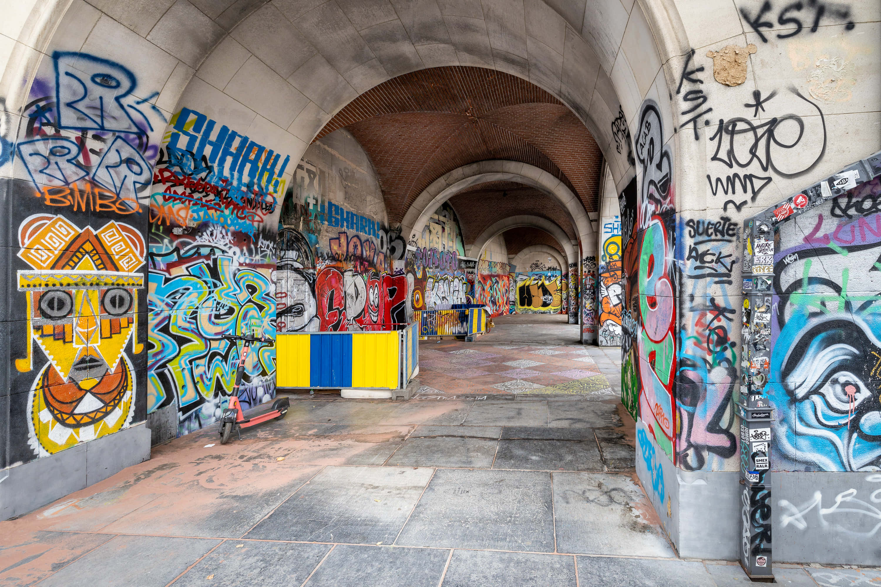 Graffiti Art 桌布 壁紙 — 一條充滿活力的塗鴉隧道，在日光下，拱形石牆上佈滿色彩繽紛的壁畫和標籤。