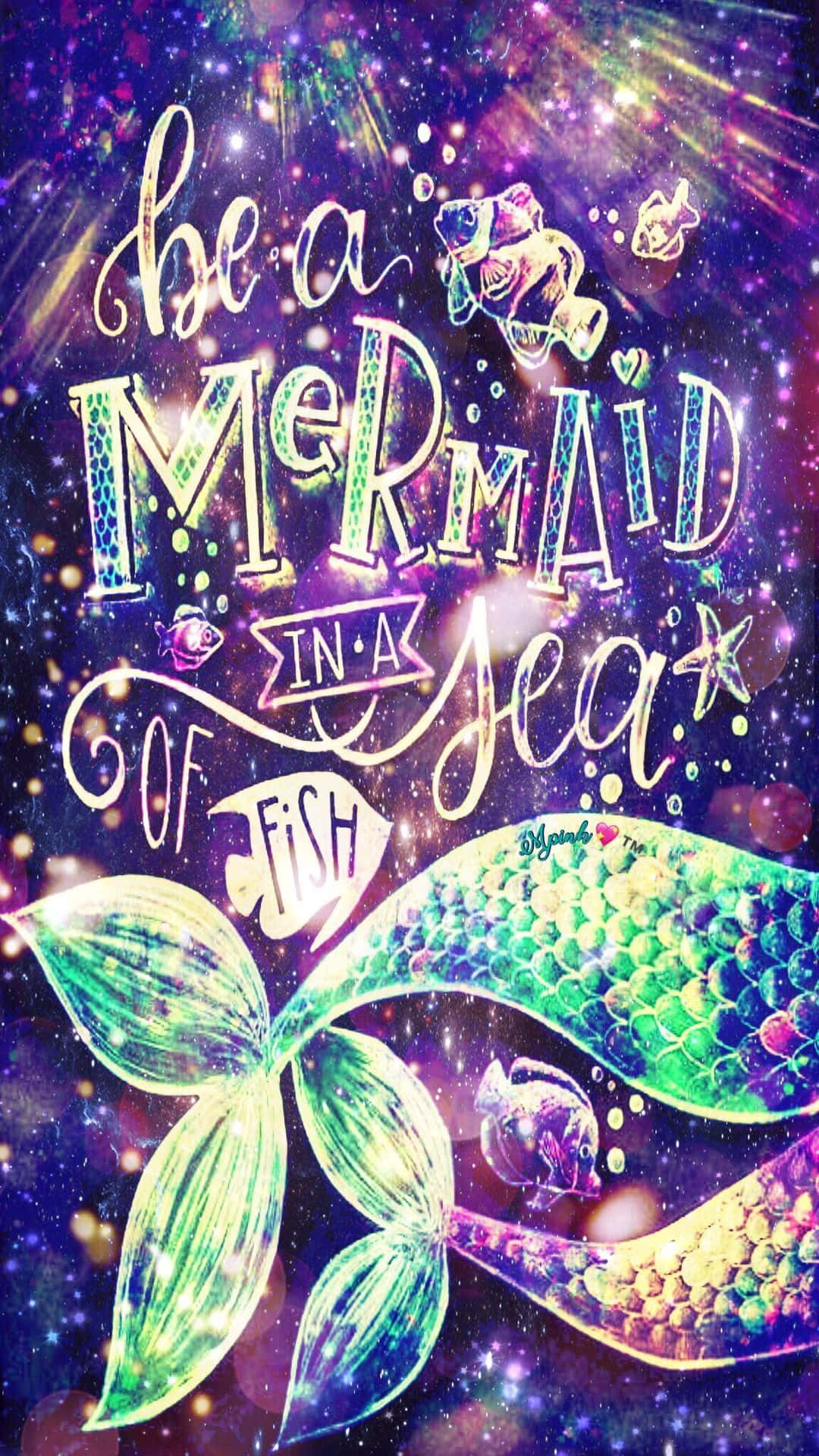 美人魚 桌布 壁紙 — 一條充滿活力的宇宙美人魚尾巴和魚在閃爍的紫色星系中游動，並有閃閃發光的文字寫著『在魚群中做一條美人魚』。