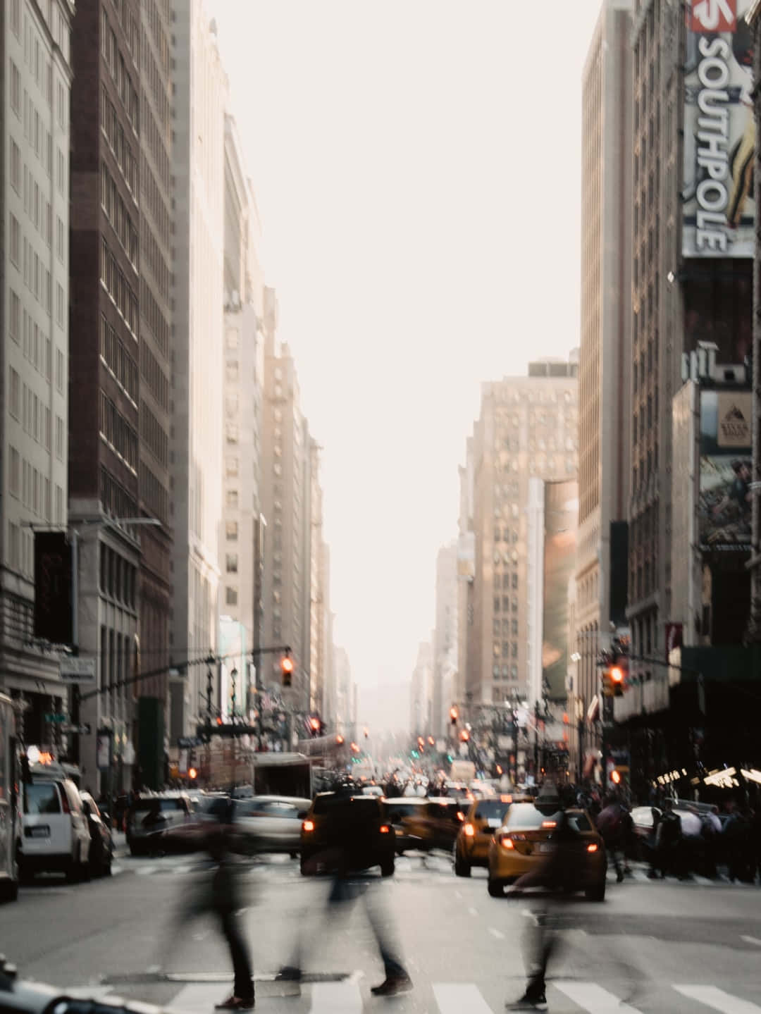 Motion Blur 桌布 壁紙 — 一條動態模糊的城市街道，黃色計程車和行人在高聳建築物之間穿行，天空朦朧。