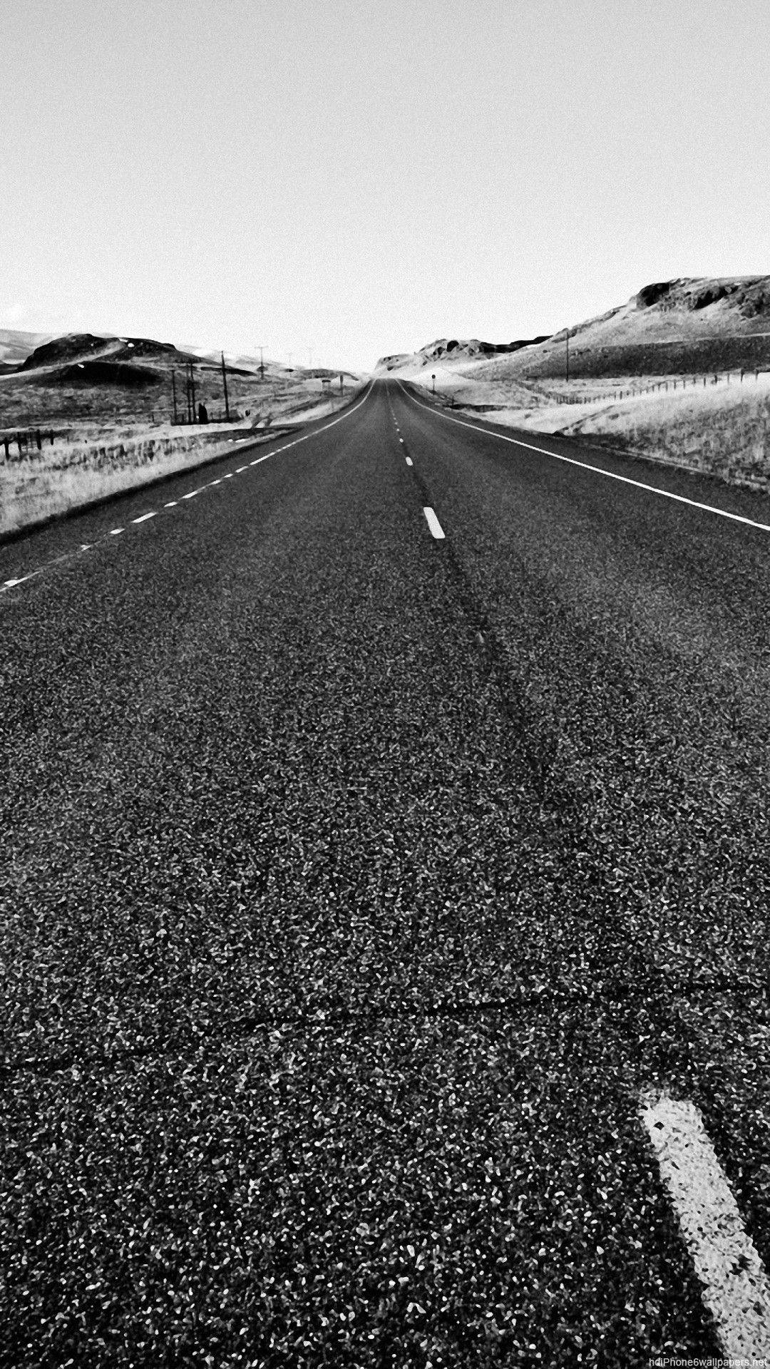 Road 桌布 壁紙 — 一條單色高速公路在廣闊天空下，無盡地穿過荒蕪的山丘。