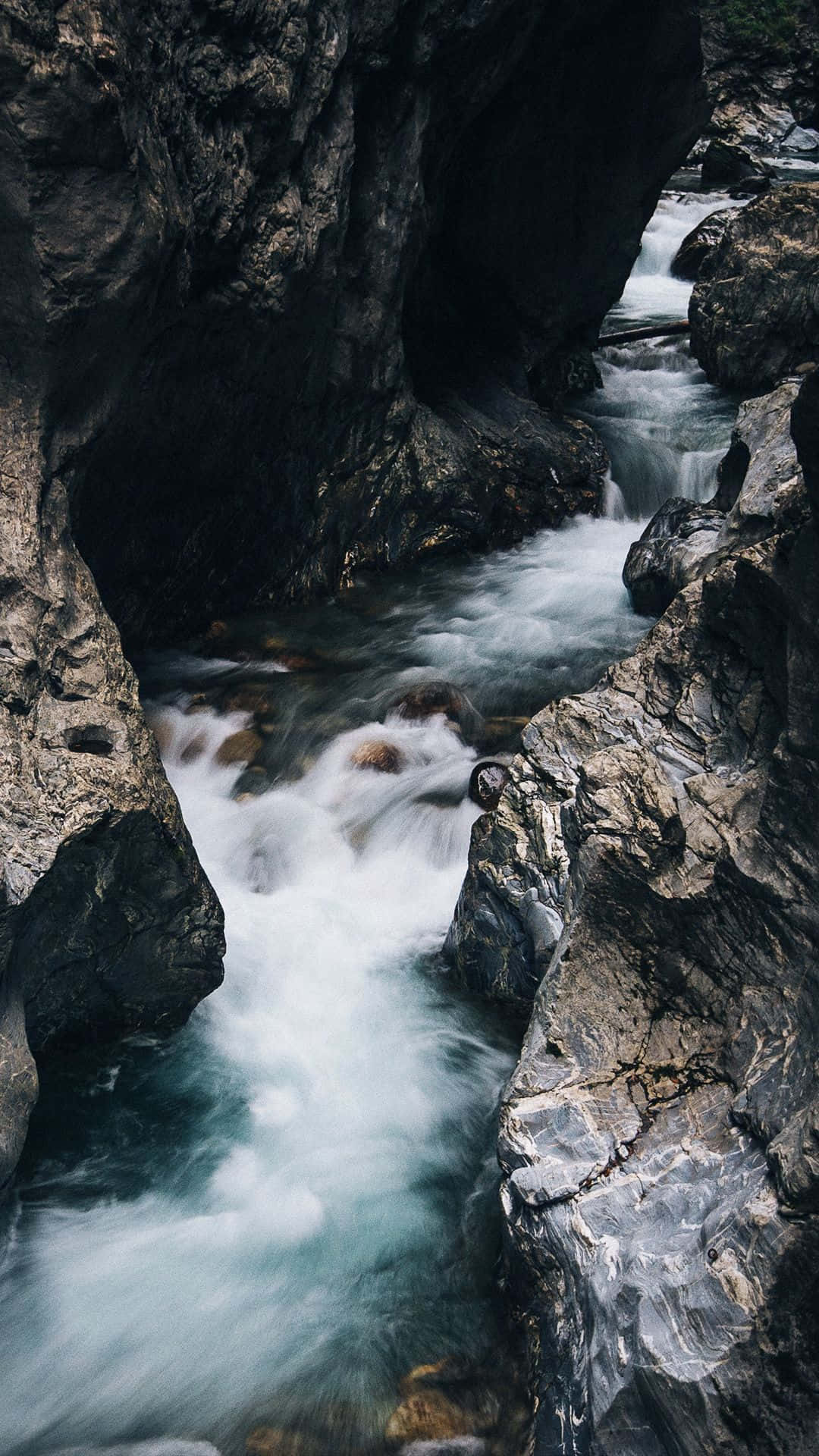 Creek 桌布 壁紙 — 一條奔騰的綠松石河流在黑暗崎嶇的峽谷壁中穿行，構成戲劇性的自然景象。